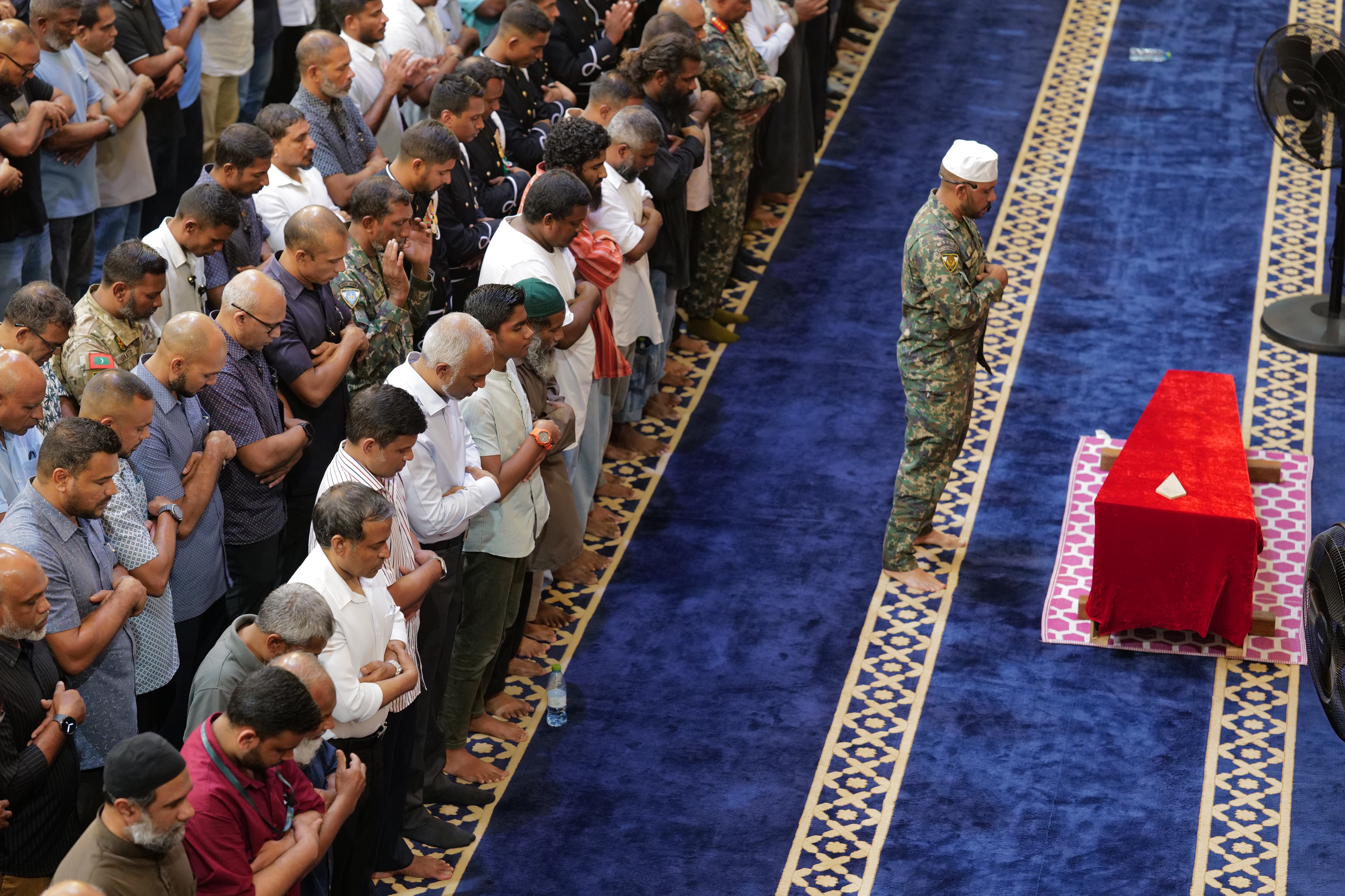 El presidente de Maldivas, Mohamed Muizzu, junto a miembros de la Fuerza Nacional de Defensa, reza frente a los restos del buzo militar Mohamed Mahudhee, quien murió durante la operación de búsqueda y rescate de cuatro buceadores italianos, durante su funeral en Malé, Maldivas, el sábado