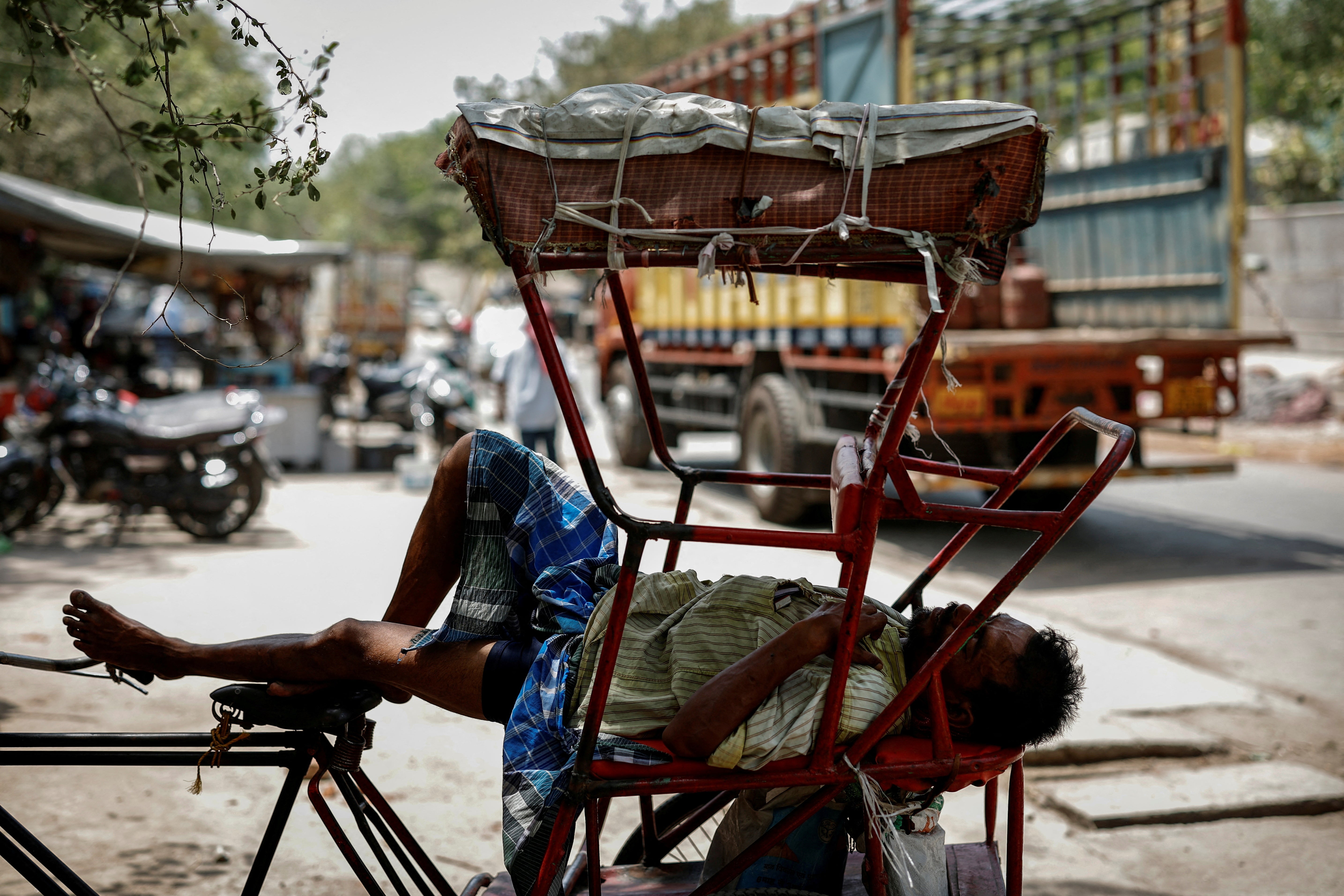 Un hombre duerme en su bicitaxi durante una ola de calor en Delhi, India