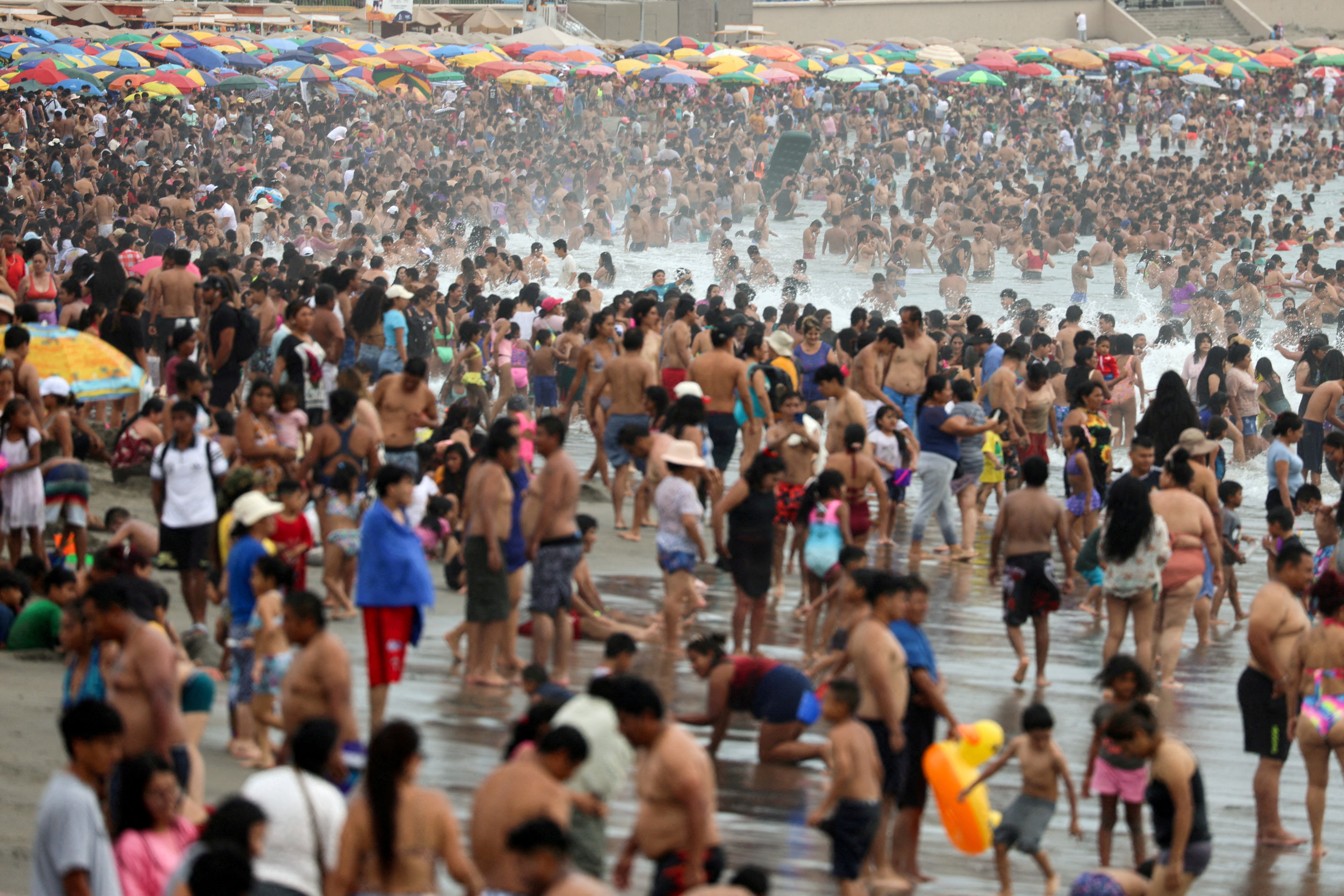 Los bañistas disfrutan de un día de verano debido a las altas temperaturas en la playa de Agua Dulce, en el distrito de Chorrillos, Lima, Perú