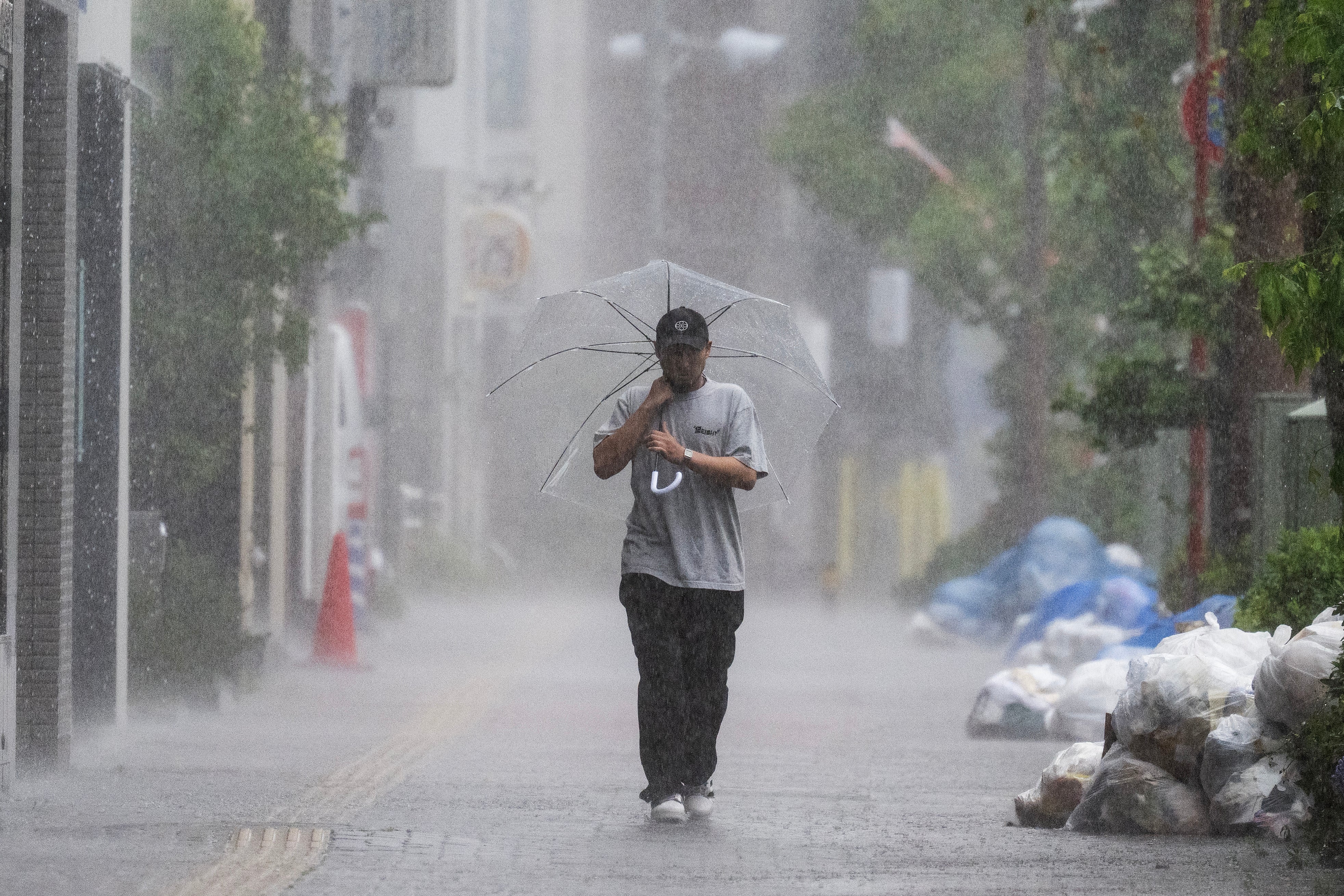 Un hombre recorre una acera en medio de las fuertes lluvias causadas por la tormenta tropical severa Jangmi en Tokio