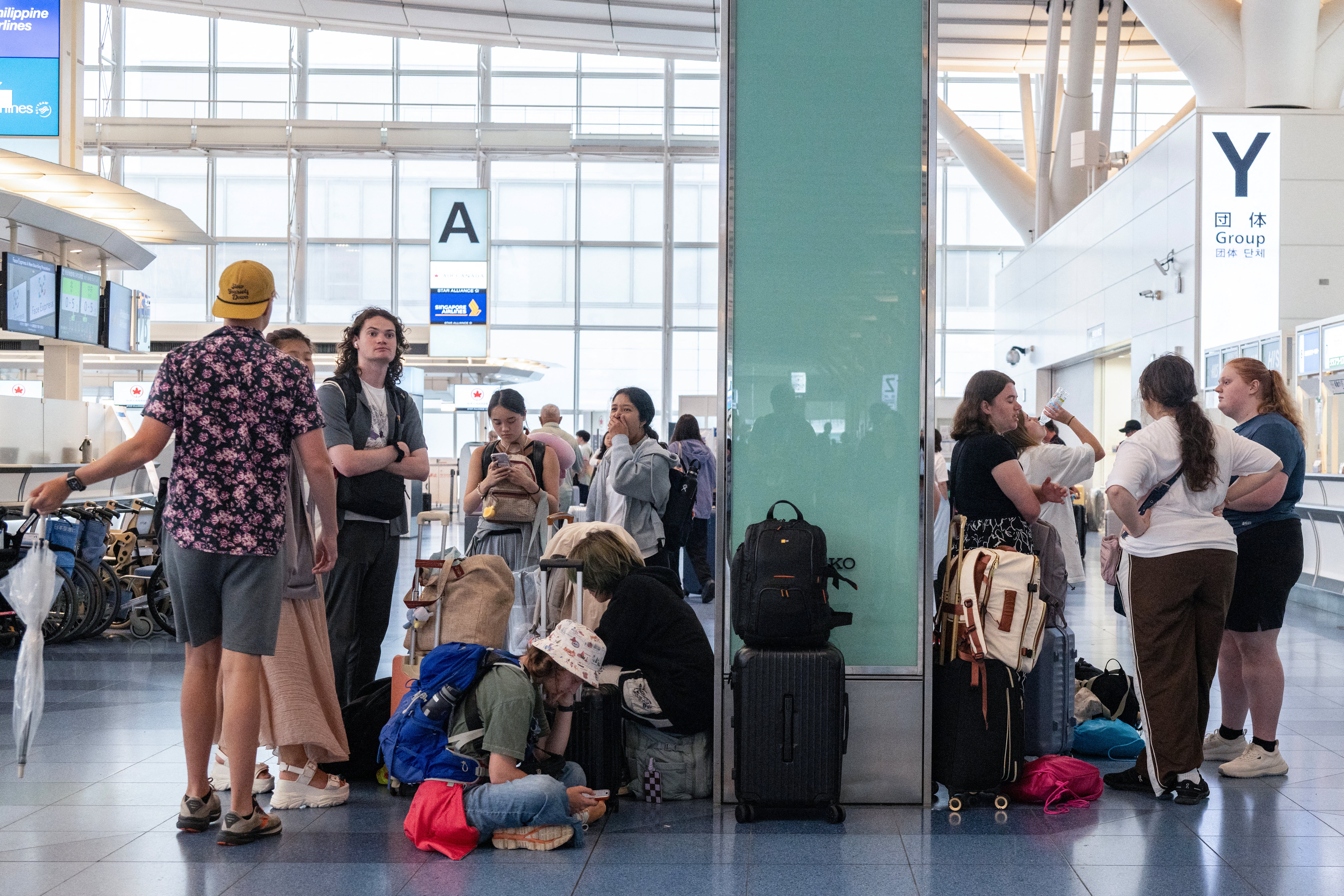 Pasajeros aguardan en la terminal internacional del aeropuerto de Haneda tras cancelaciones y fuertes retrasos causados por la tormenta tropical Jangmi en Tokio