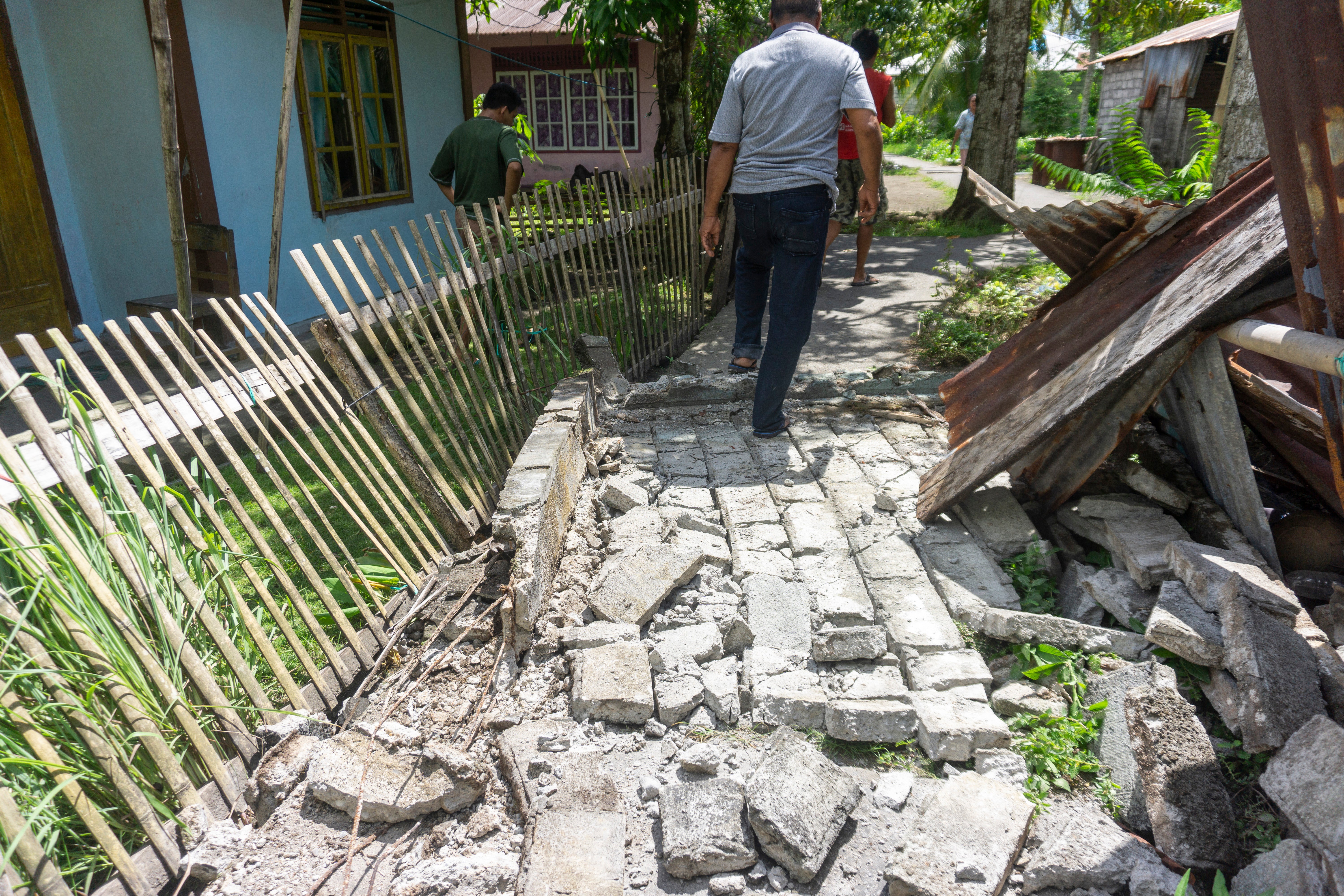 Personas caminan entre los daños en una zona residencial de la aldea de Peta Timur, en las islas Sangihe, Indonesia, tras el terremoto de magnitud 7,8 frente al sur de Filipinas, el 8 de junio de 2026