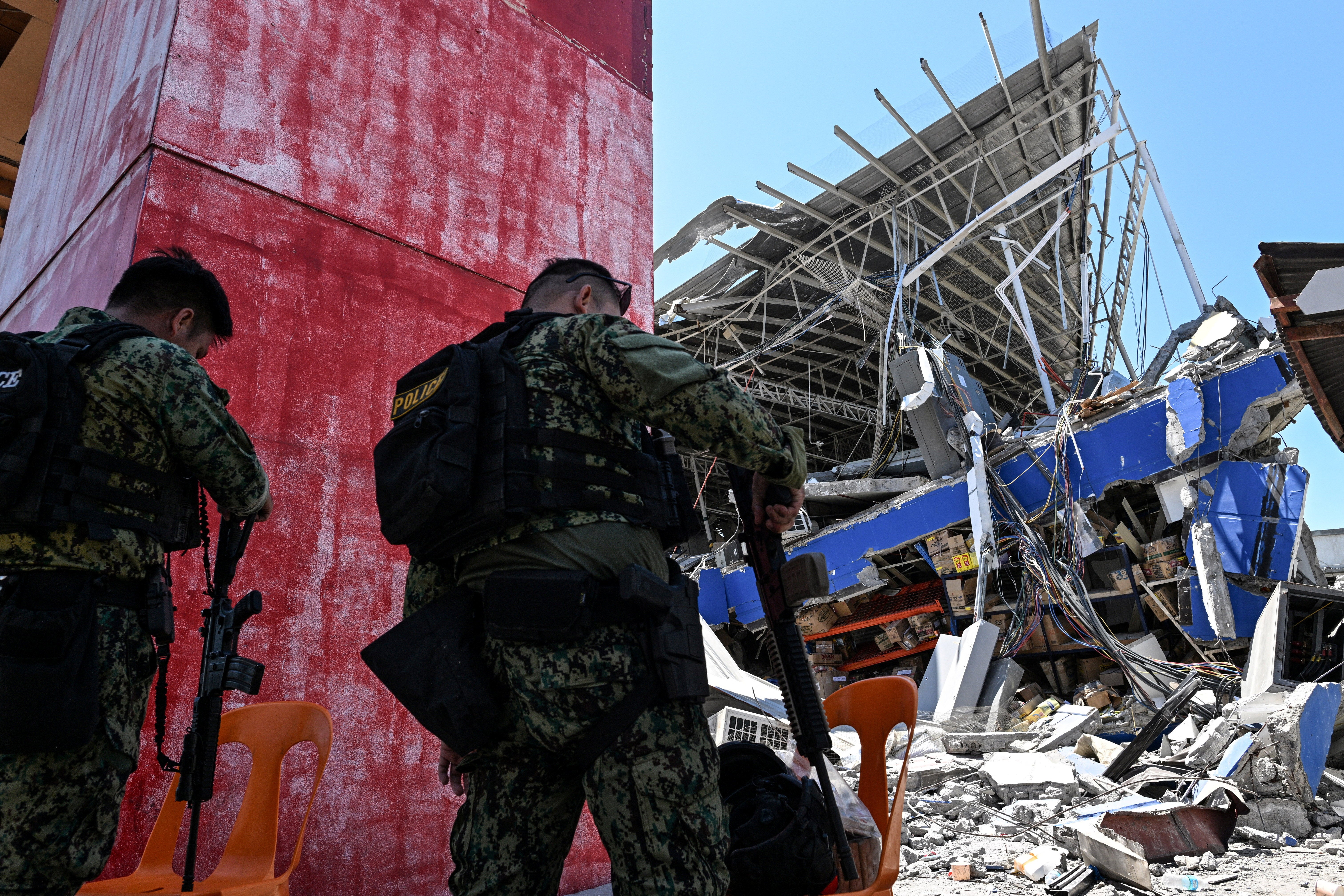La policía acordonó una tienda de comestibles derrumbada un día después de que un fuerte terremoto sacudiera Calumpang, en General Santos (Filipinas)