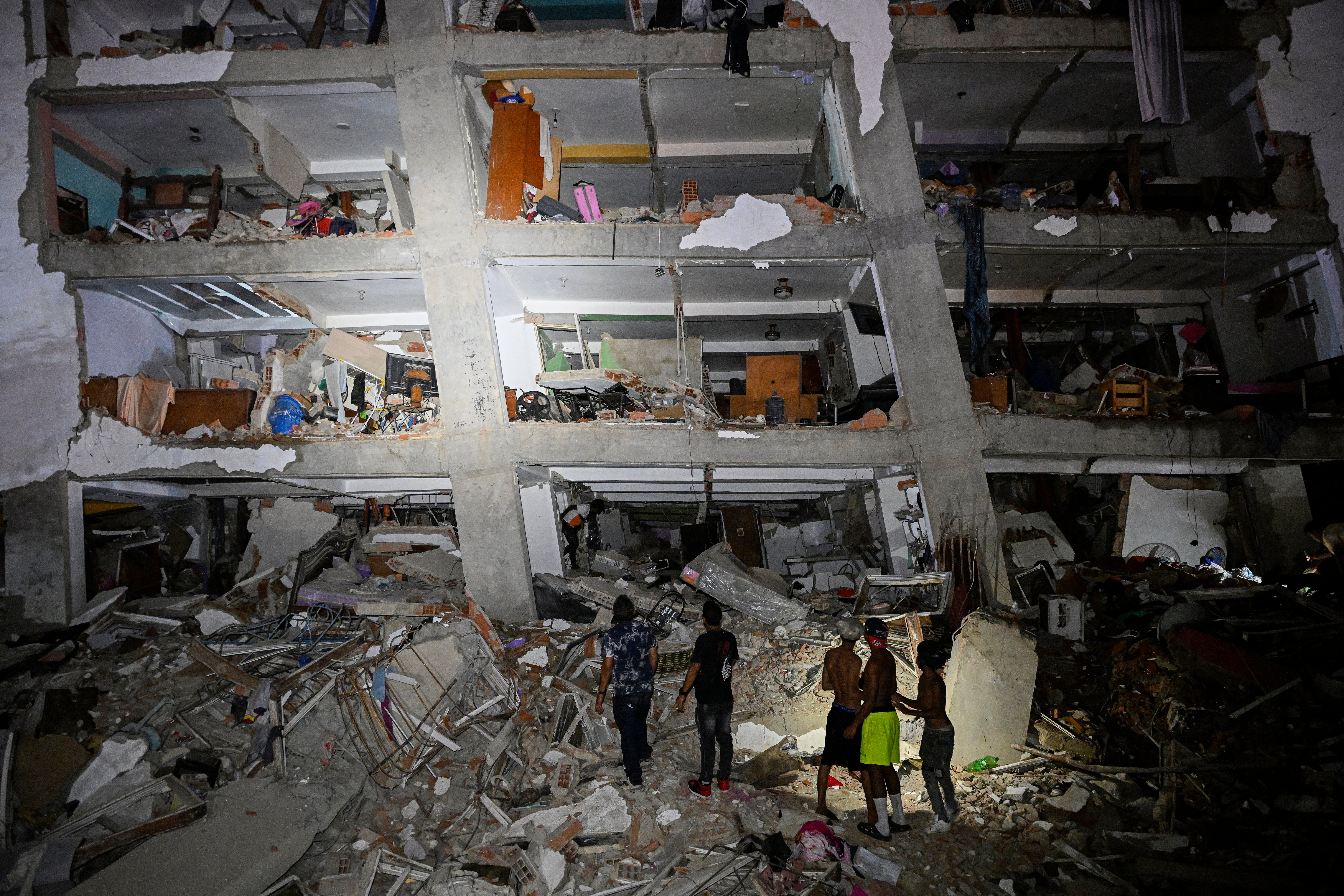 Personas permanecen entre los escombros junto a un edificio dañado tras el terremoto en Catia La Mar, estado La Guaira, Venezuela