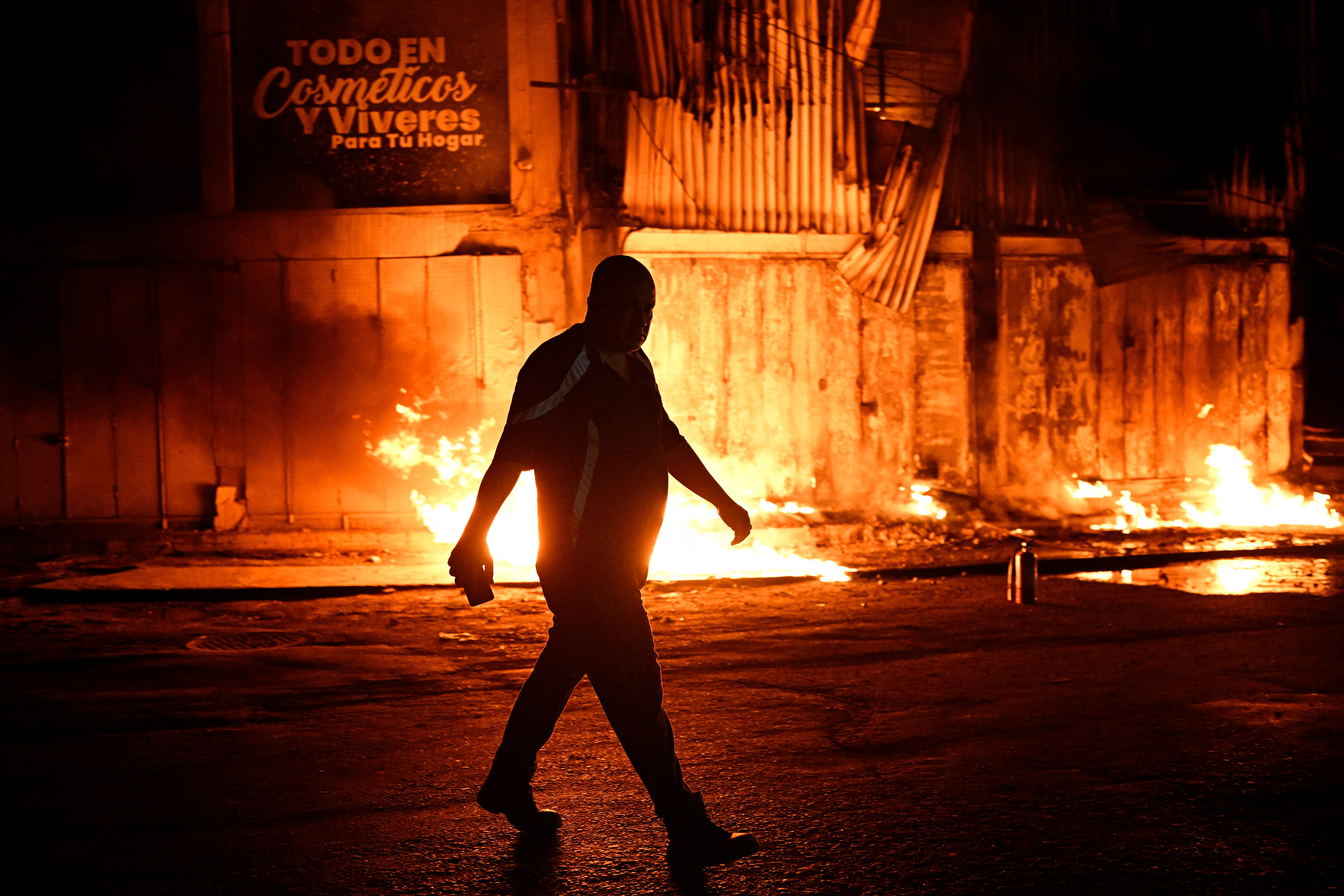 Un hombre camina junto a un incendio frente a un edificio tras el terremoto en Catia La Mar, estado La Guaira, a unos 30 kilómetros al noroeste de Caracas