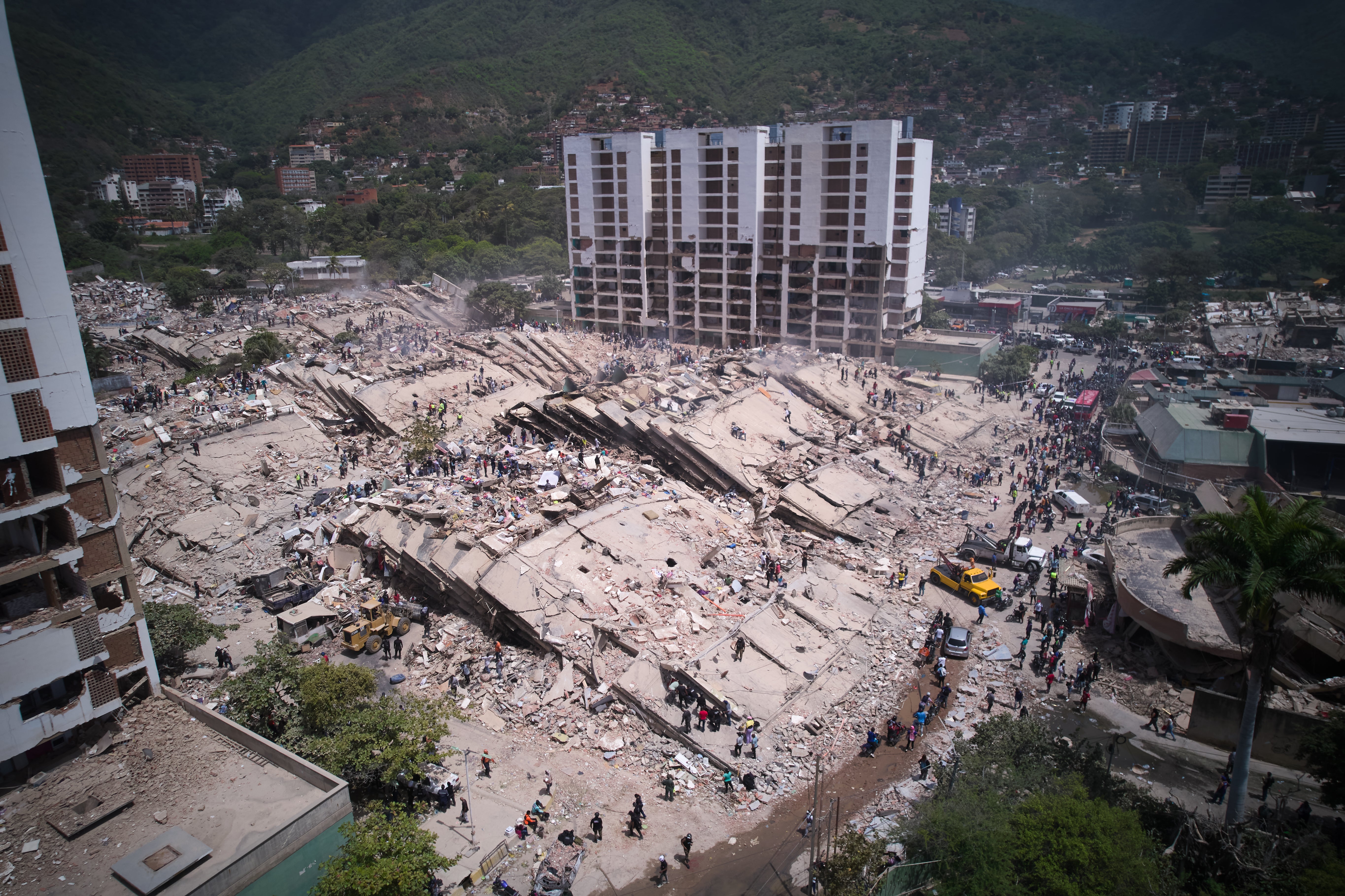 Residentes y rescatistas buscan entre los escombros dos días después de un terremoto, el viernes 26 de junio de 2026, en La Guaira, Venezuela