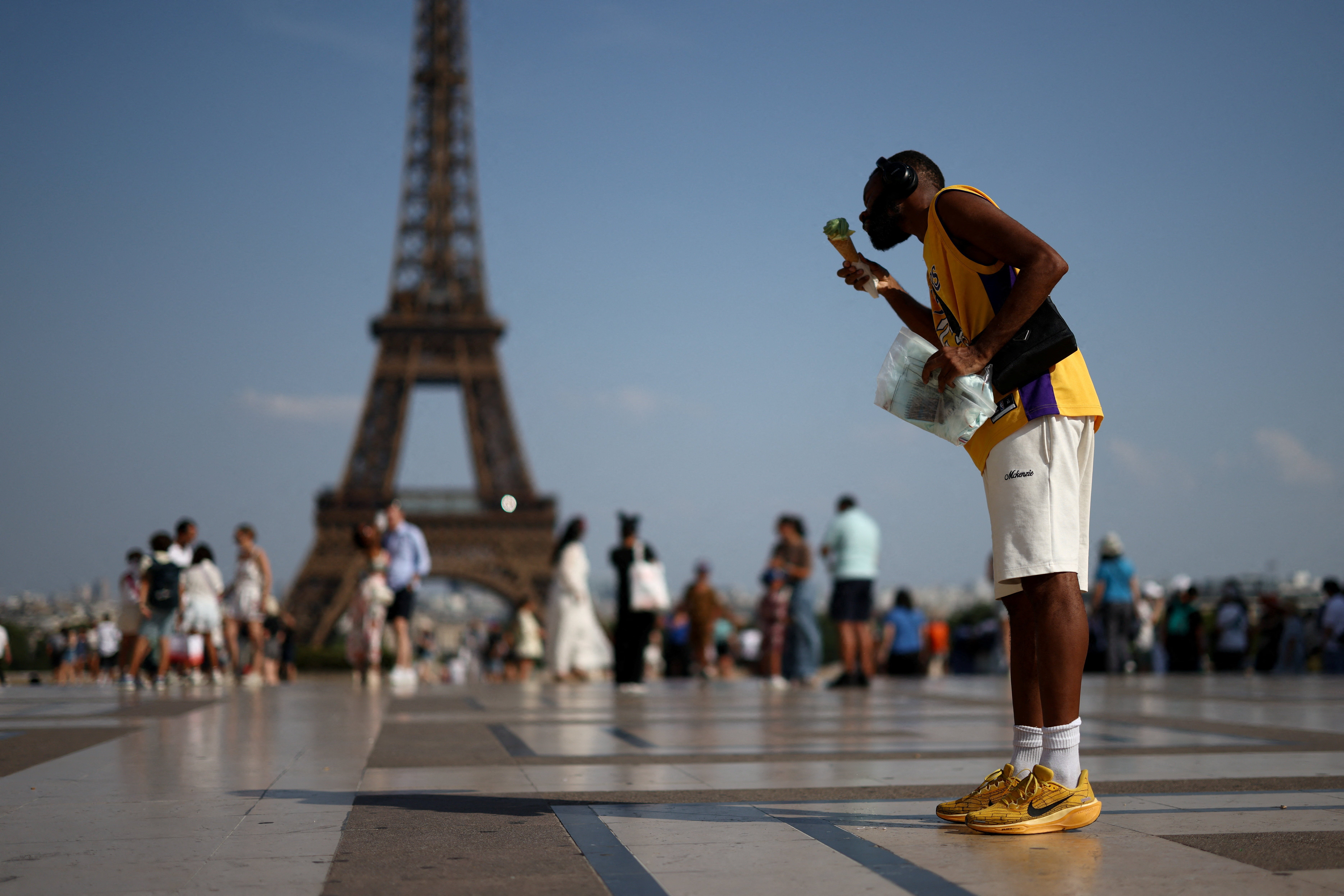 Una persona come un helado frente a la Torre Eiffel durante la ola de calor en París, Francia