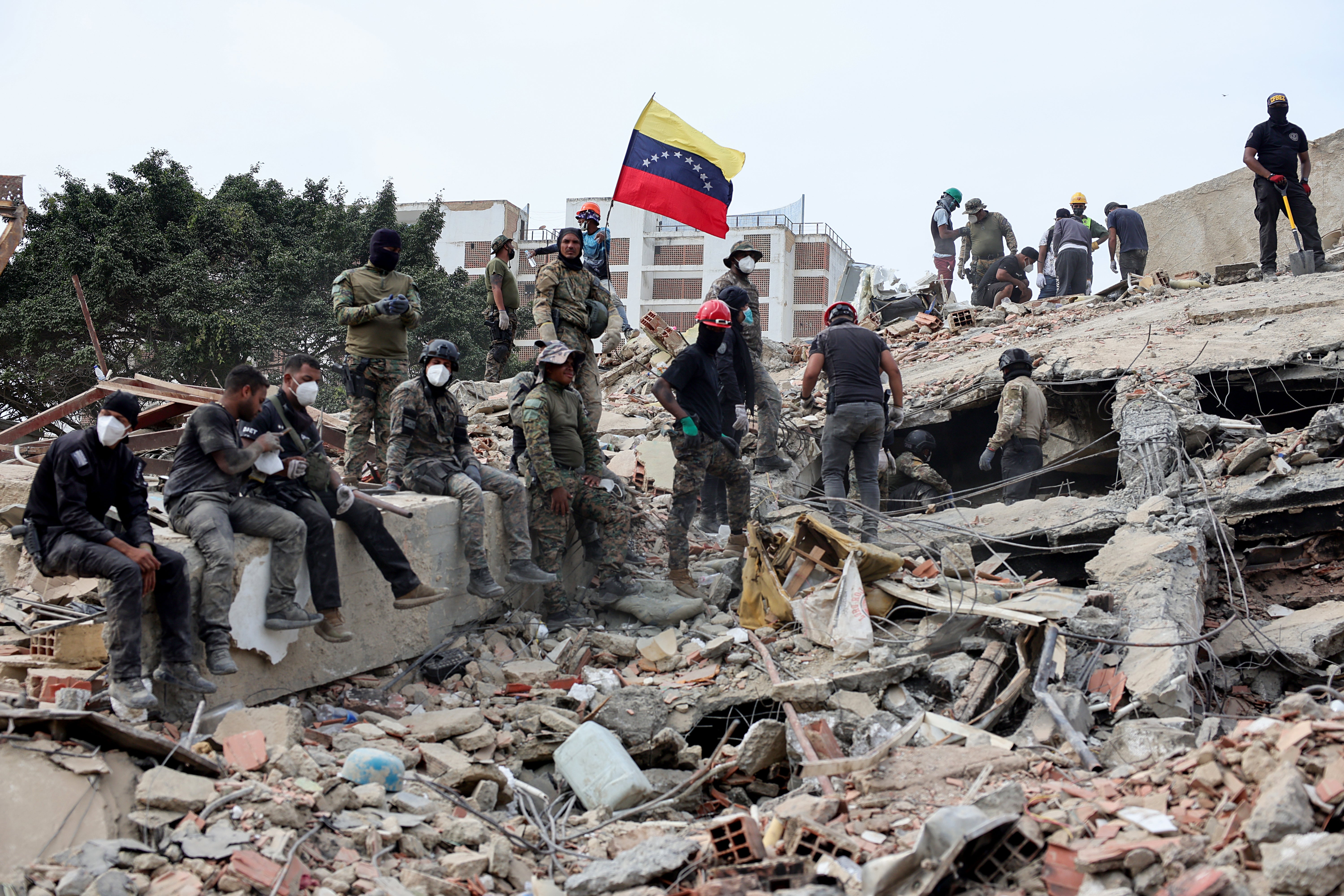 Los equipos de rescate buscan a las víctimas en un edificio derrumbado, mientras alguien iza una bandera venezolana tras el terremoto de magnitud 7,2 que sacudió Venezuela y otras regiones del Caribe