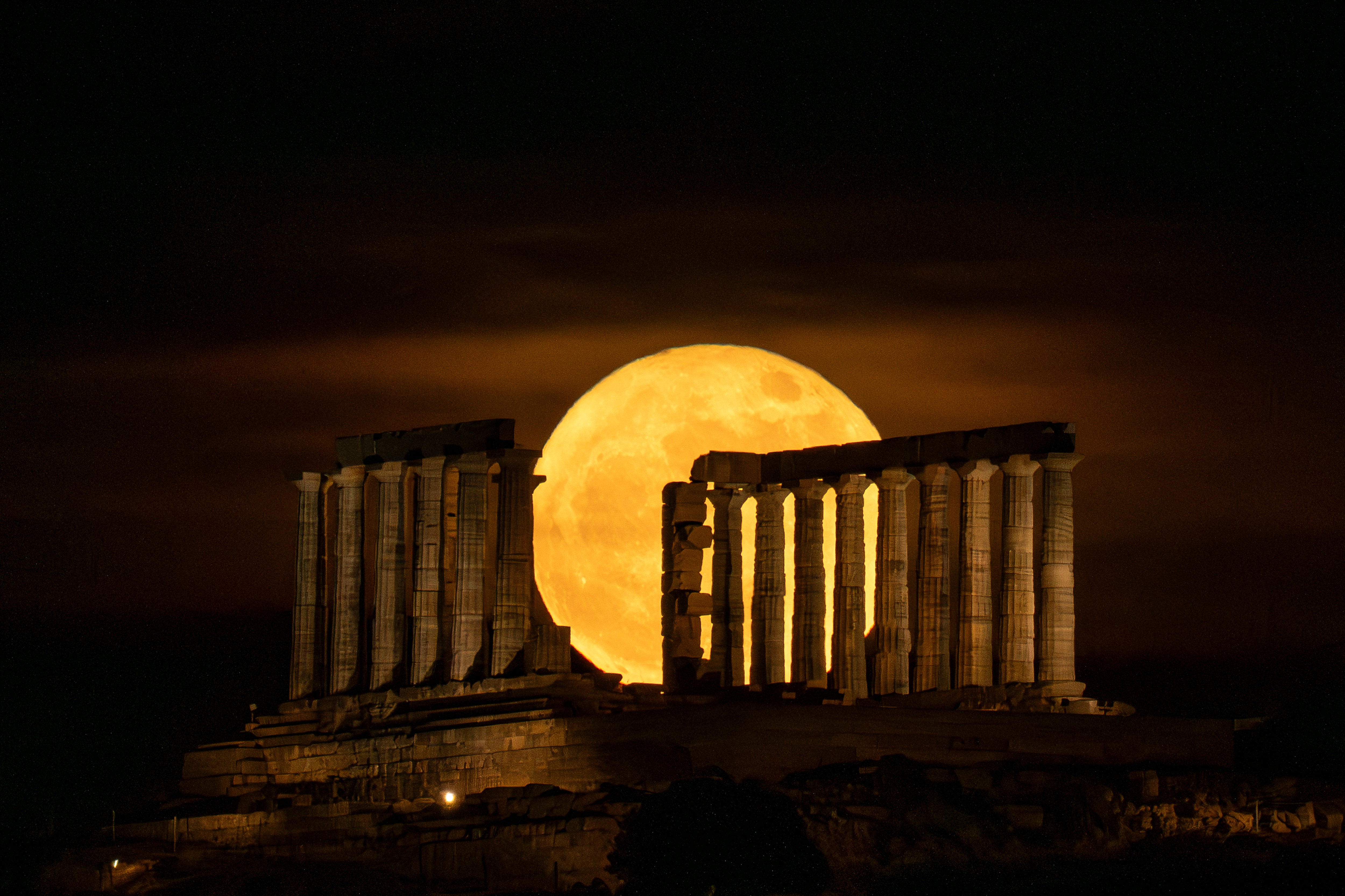 La luna llena sale detrás del antiguo templo griego de Poseidón, en el cabo de Sounion, al sur de Atenas, el 31 de mayo de 2026