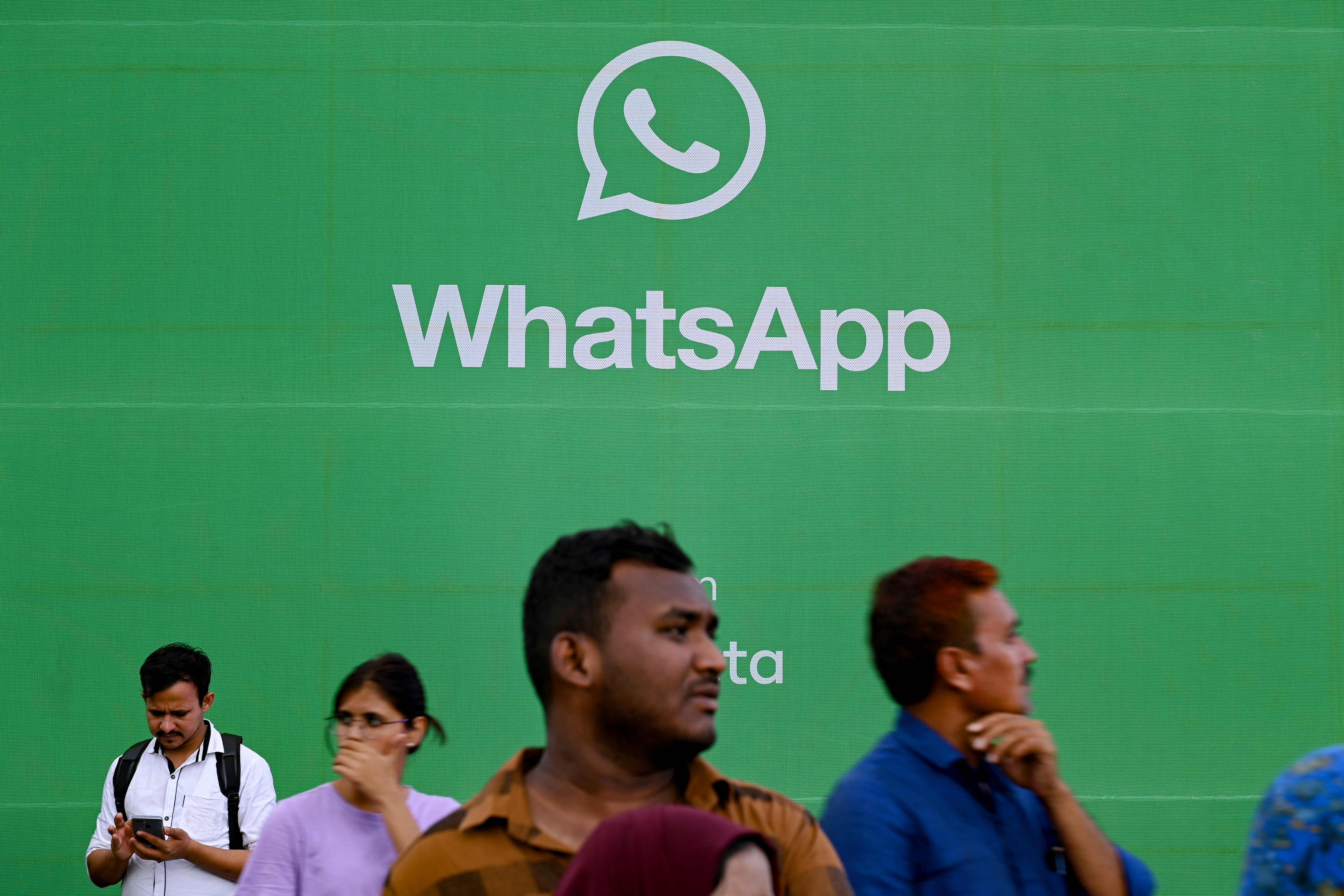 Unos turistas pasan junto a un expositor de la aplicación de mensajería WhatsApp en Bombay (India), el 25 de agosto de 2023