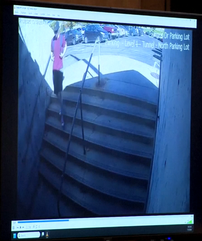 En una de las grabaciones, una persona con una camiseta roja y pantalones cortos desciende por una escalera del campus