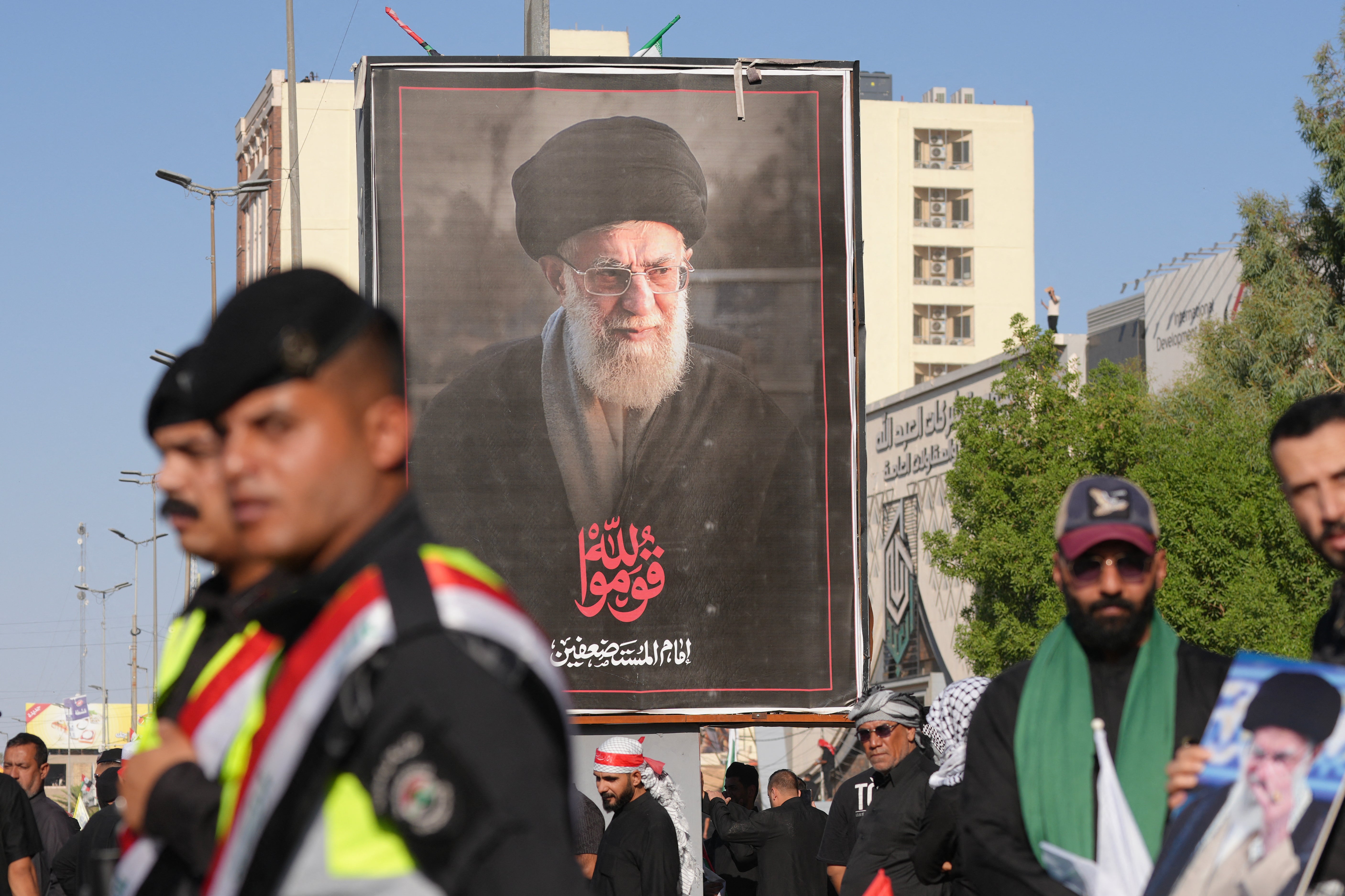 Las fuerzas de seguridad montan guardia frente a un retrato del líder supremo iraní Ali Jamenei, quien fue asesinado, mientras los dolientes se reúnen para una procesión fúnebre en Nayaf el 8 de julio de 2026