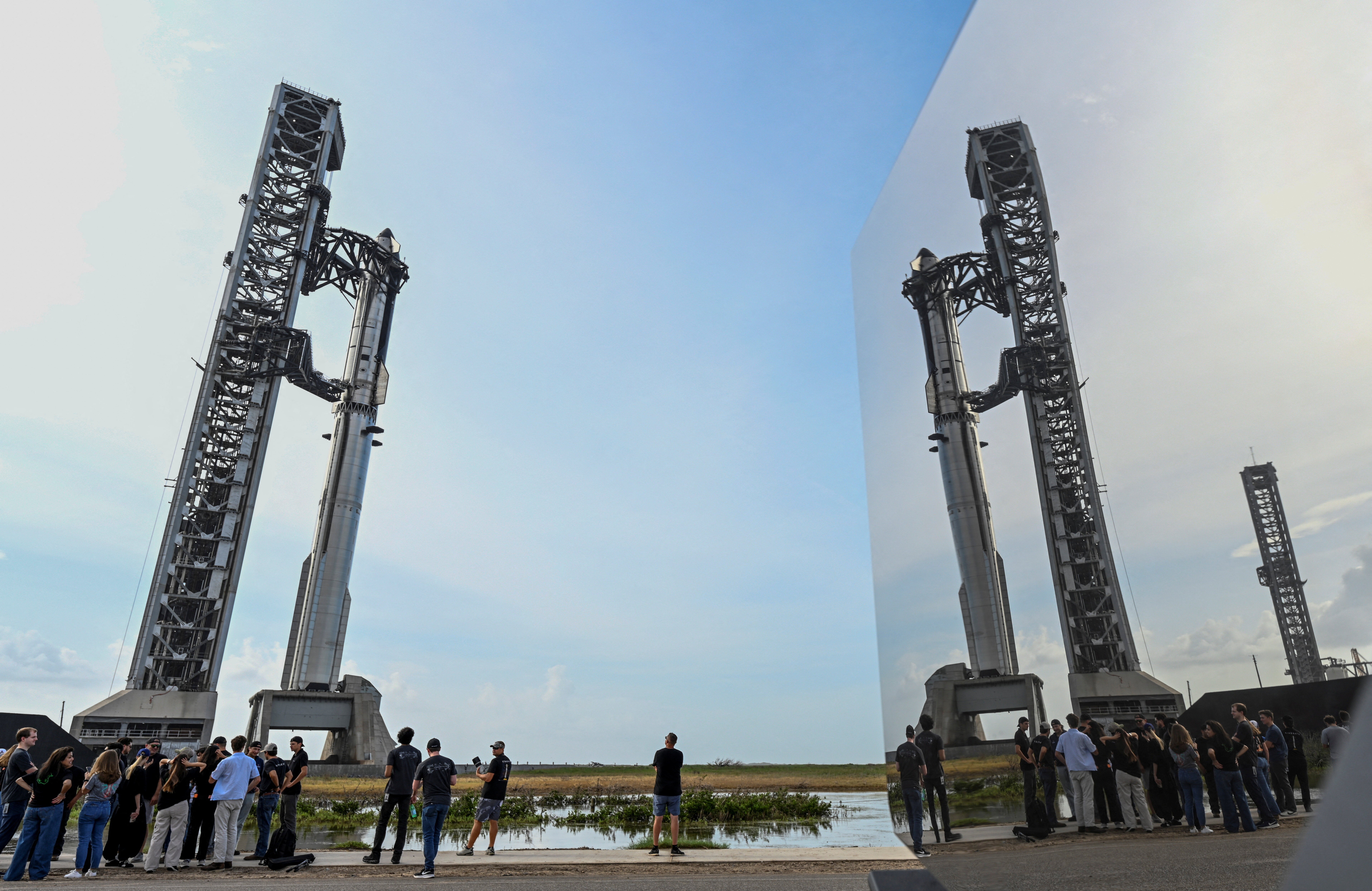 <p>Empleados de SpaceX se reflejan en el panel lateral de una Tesla Cybertruck mientras se reúnen cerca de la nave Starship y el propulsor Super Heavy V3 en la plataforma 2, antes del decimotercer vuelo de prueba desde el complejo de lanzamiento de SpaceX en Starbase, Texas, el 16 de julio de 2026</p>