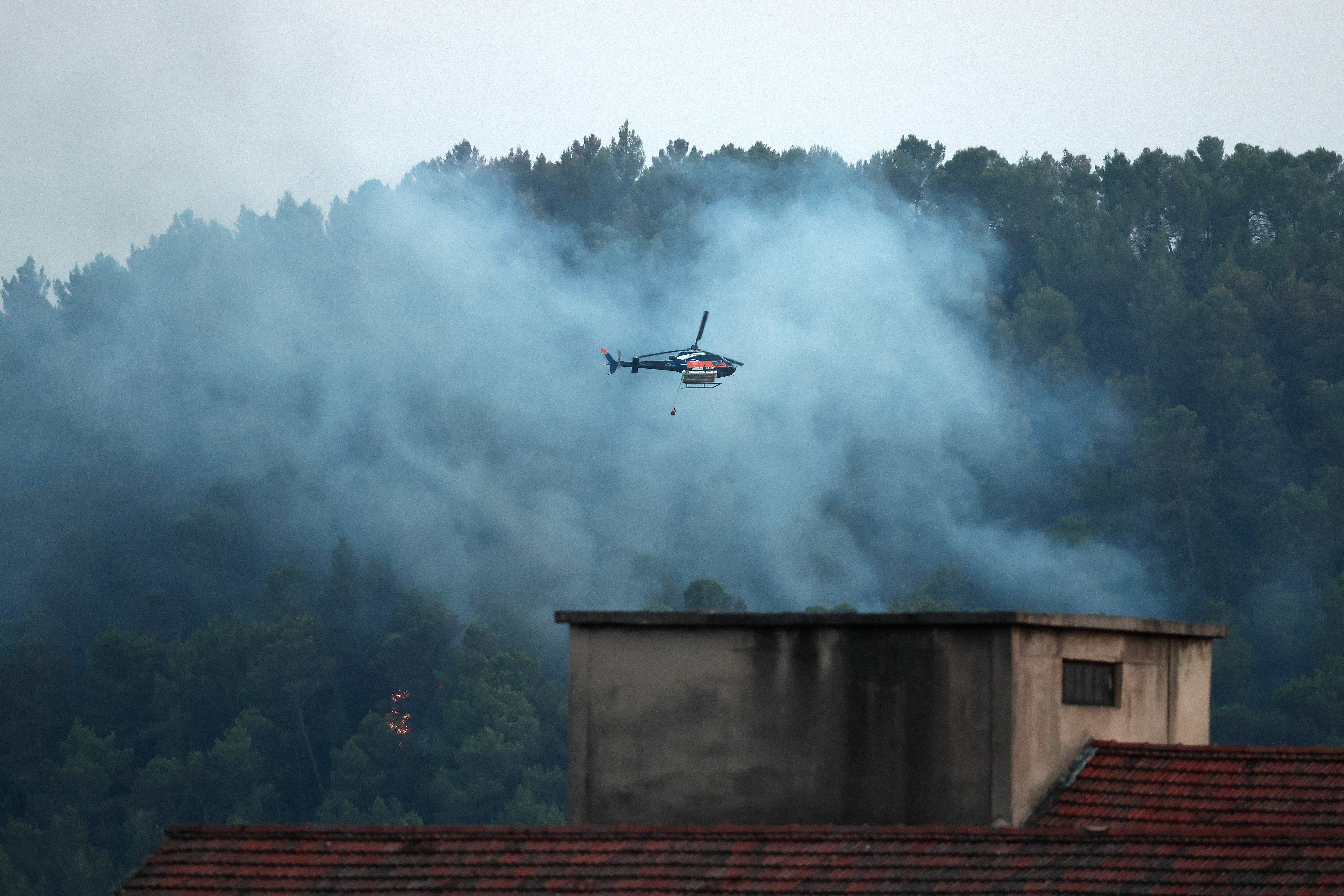 Un helicóptero cisterna, el Airbus Helicopter H125, descarga agua sobre una zona en llamas durante un incendio forestal frente a Barjols, en el sureste de Francia