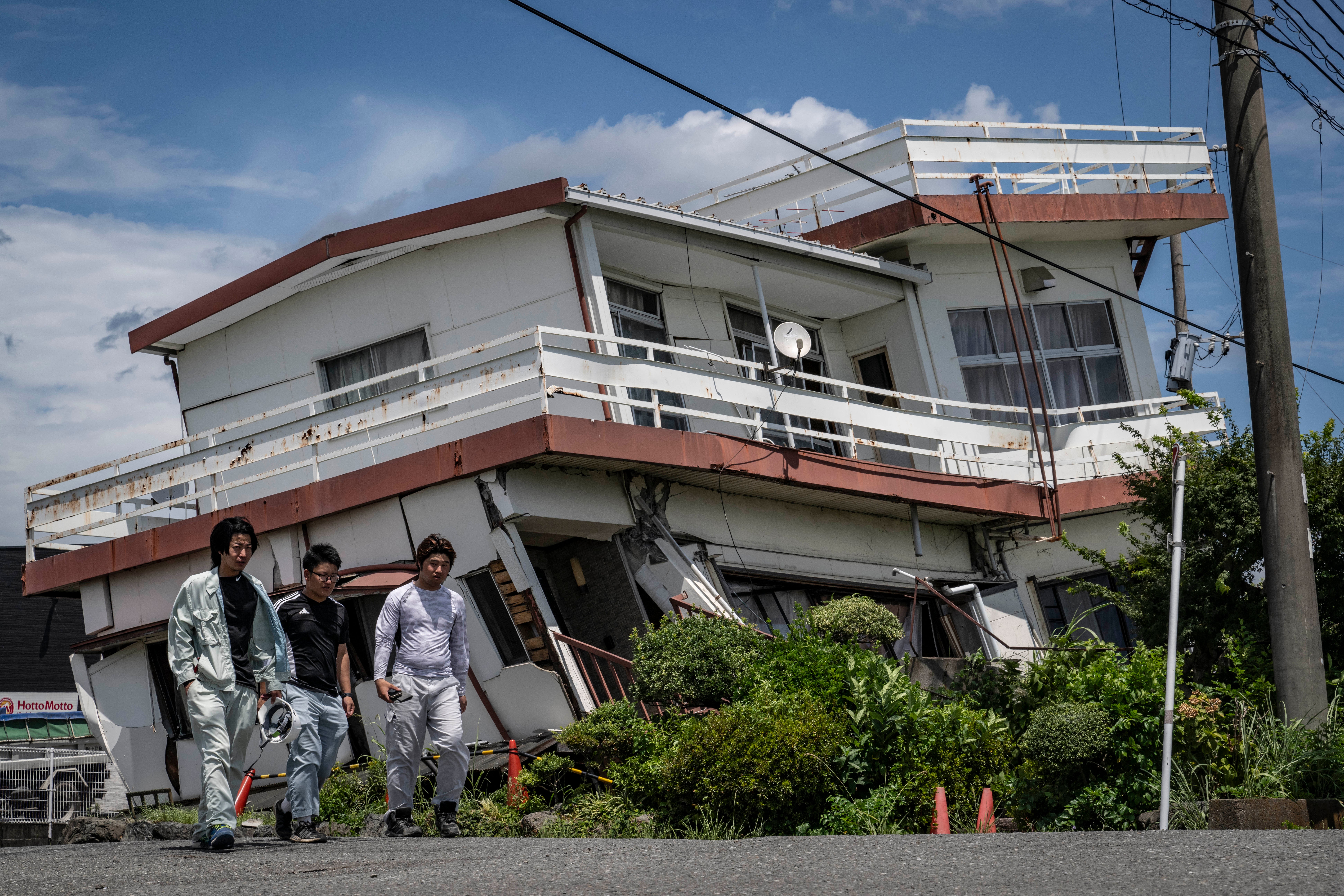 Trabajadores pasan junto a una vivienda dañada y parcialmente colapsada en Yatsushiro, prefectura de Kumamoto, un día después del terremoto que sacudió el suroeste de Japón