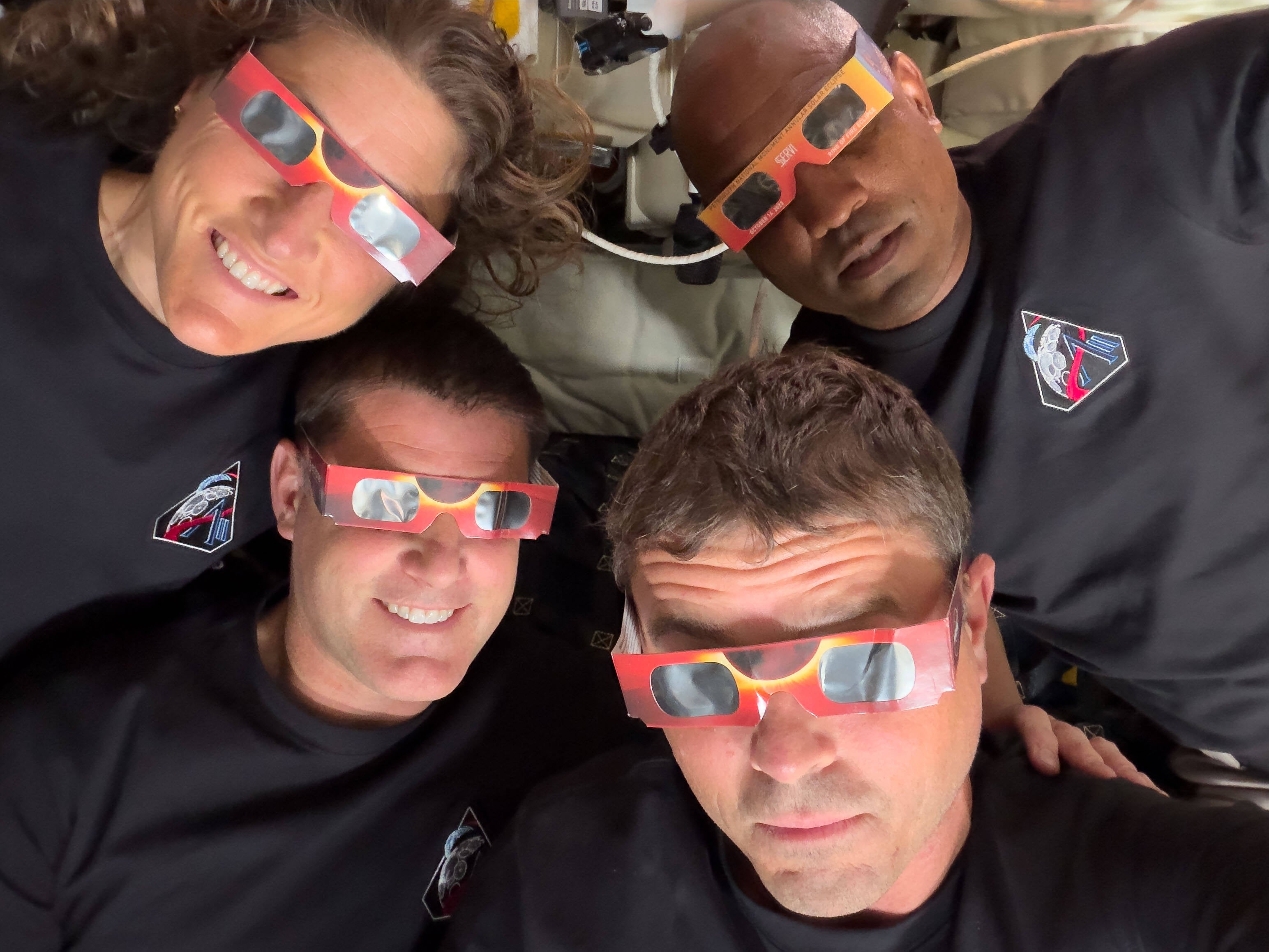 En esta imagen facilitada por la NASA, la tripulación de la misión Artemis II —en sentido antihorario desde la parte superior izquierda: la especialista de misión Christina Koch, el especialista de misión Jeremy Hansen, el comandante Reid Wiseman y el piloto Victor Glover— posa con unos espectadores del eclipse durante un sobrevuelo lunar el 6 de abril de 2026