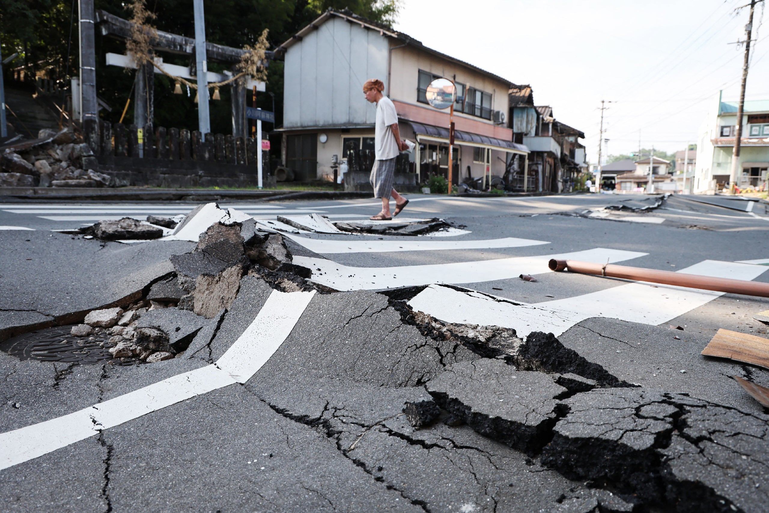 Un hombre camina por una carretera destruida en Uki, prefectura de Kumamoto