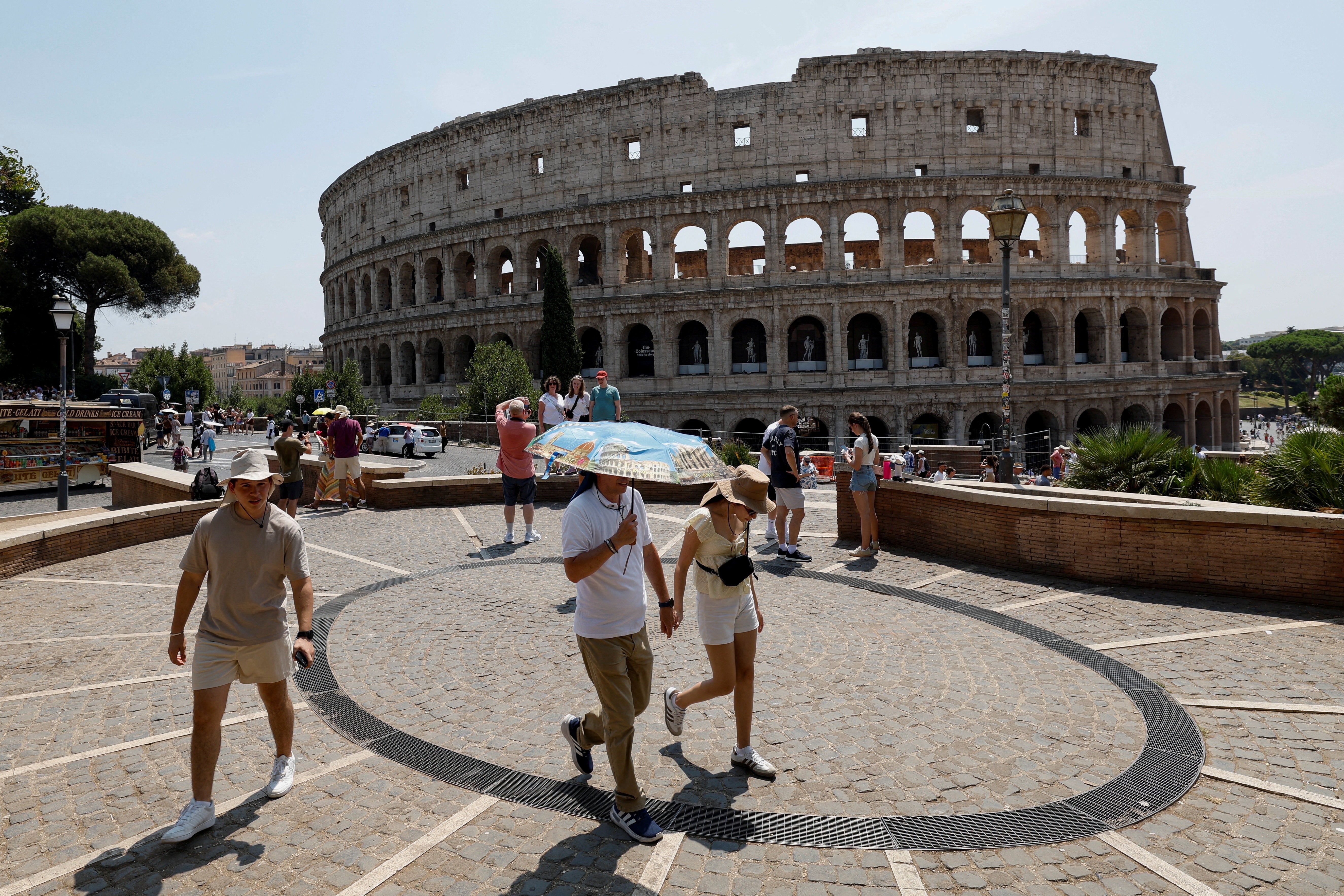 Una persona sostiene un paraguas mientras camina cerca del Coliseo durante una ola de calor en Italia