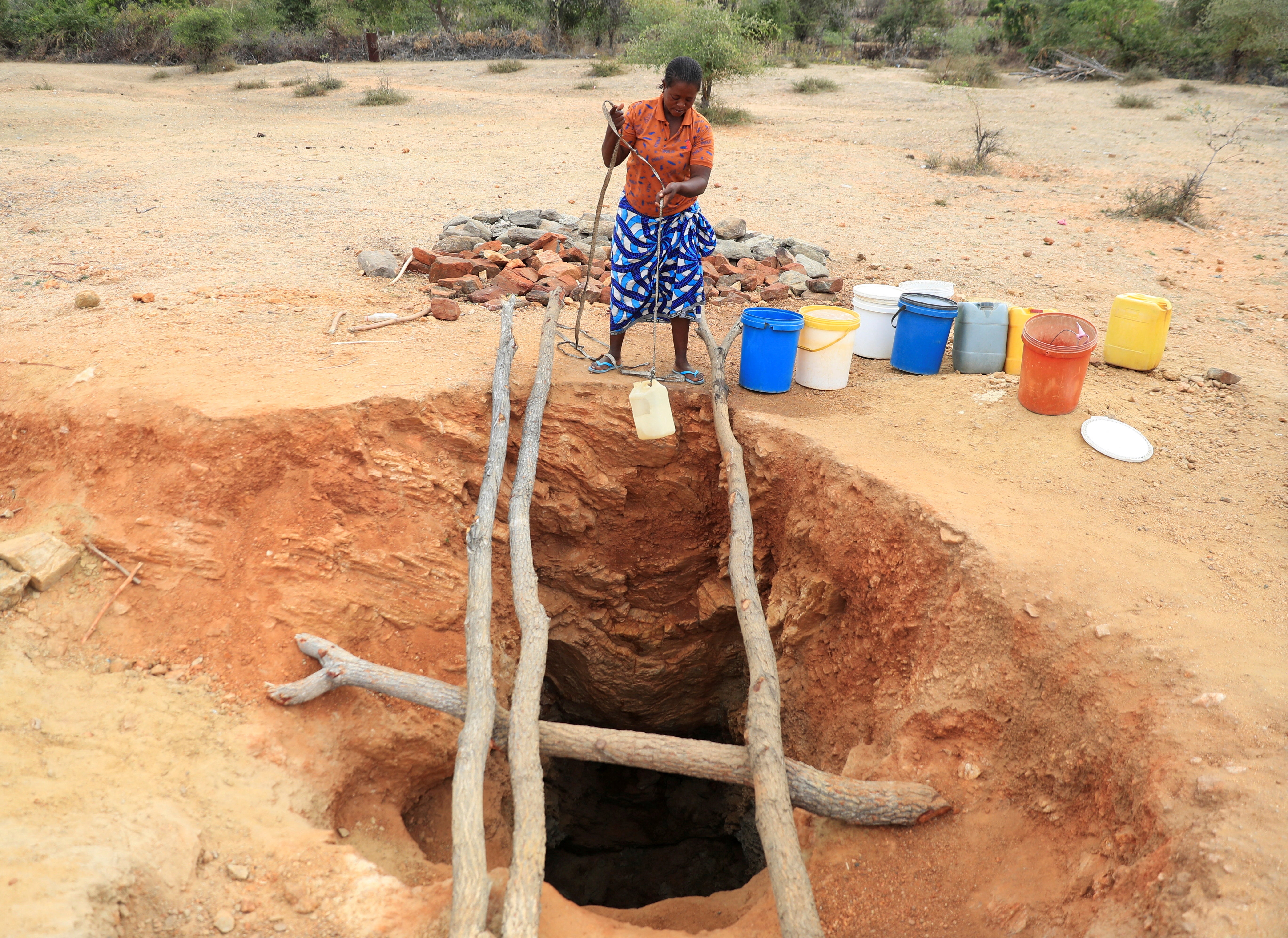 Una mujer recoge agua potable de un pozo sin protección durante una sequía provocada por El Niño en Zimbabue