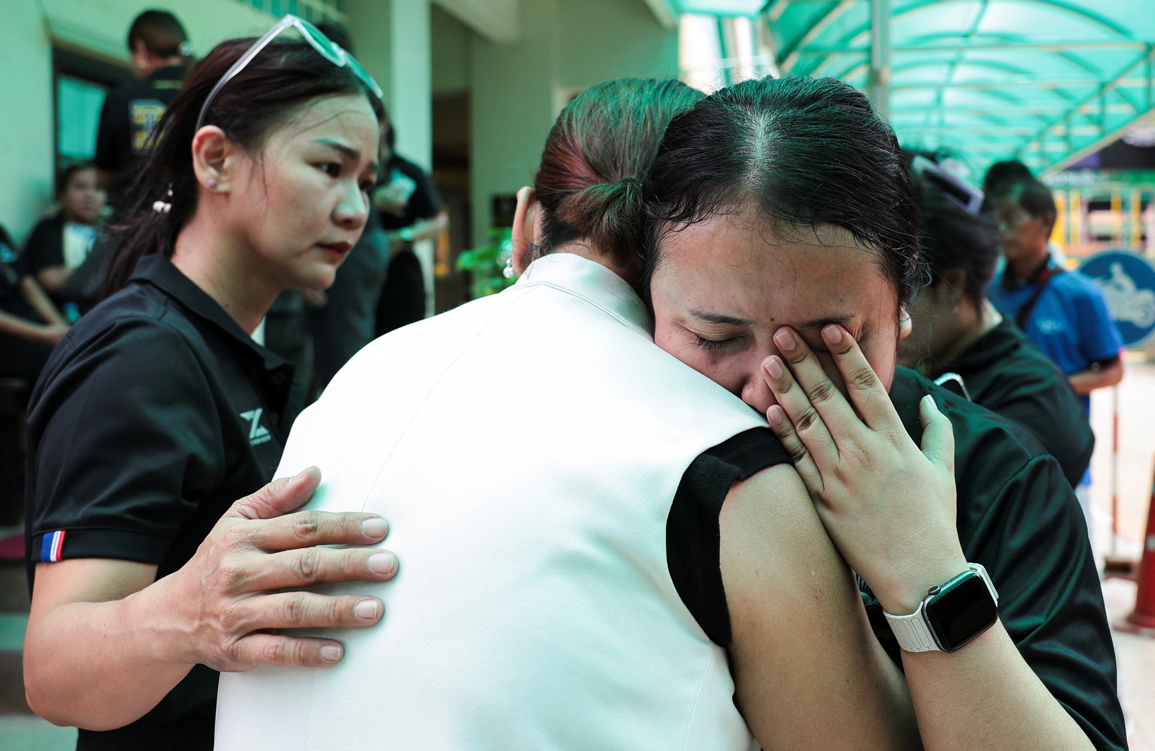 Una maestra reacciona mientras abraza a una persona en la escuela Debsirin Nonthaburi