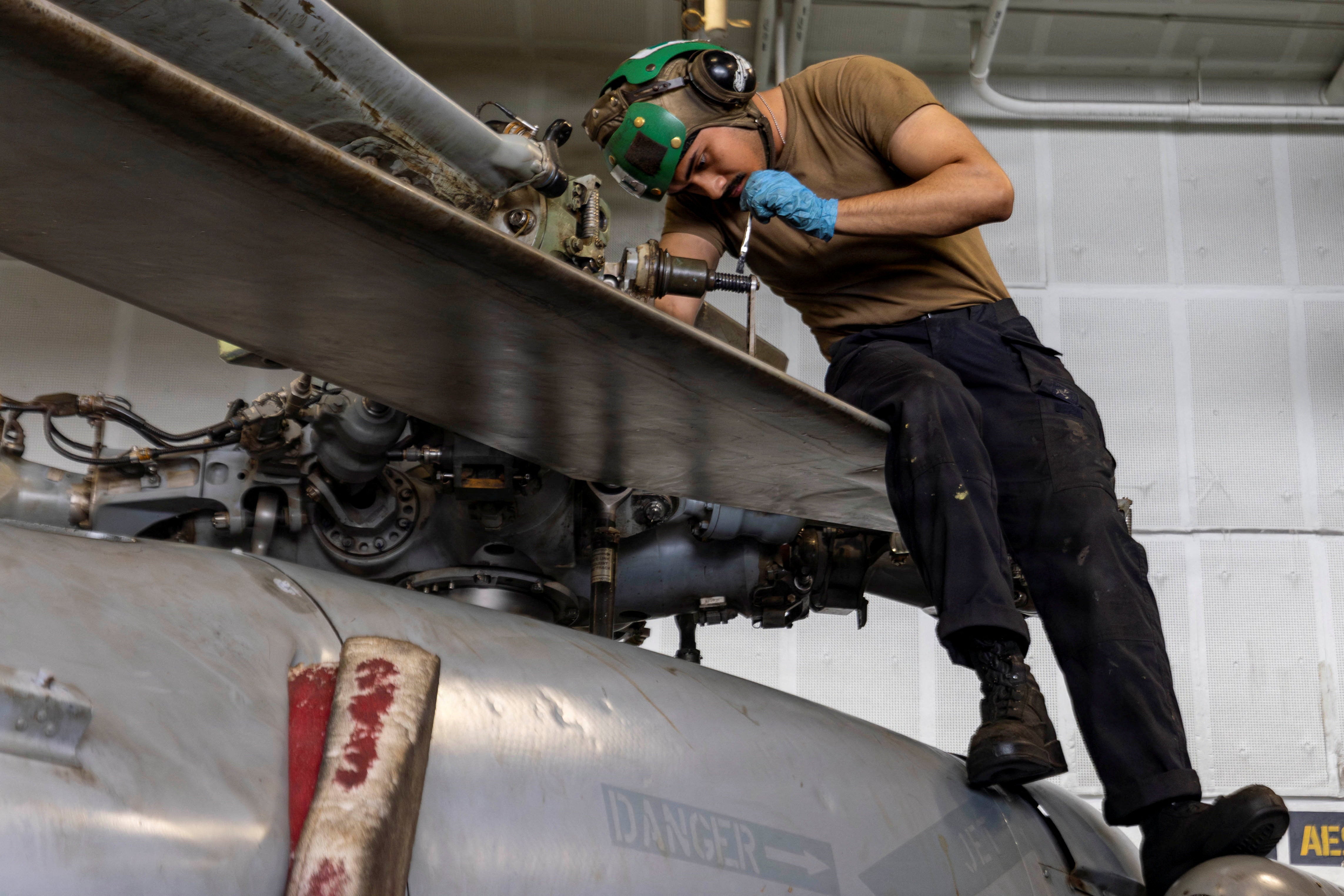 Un marinero estadounidense realiza tareas de mantenimiento en un MH-60S Sea Hawk en el hangar del USS Abraham Lincoln el 9 de agosto