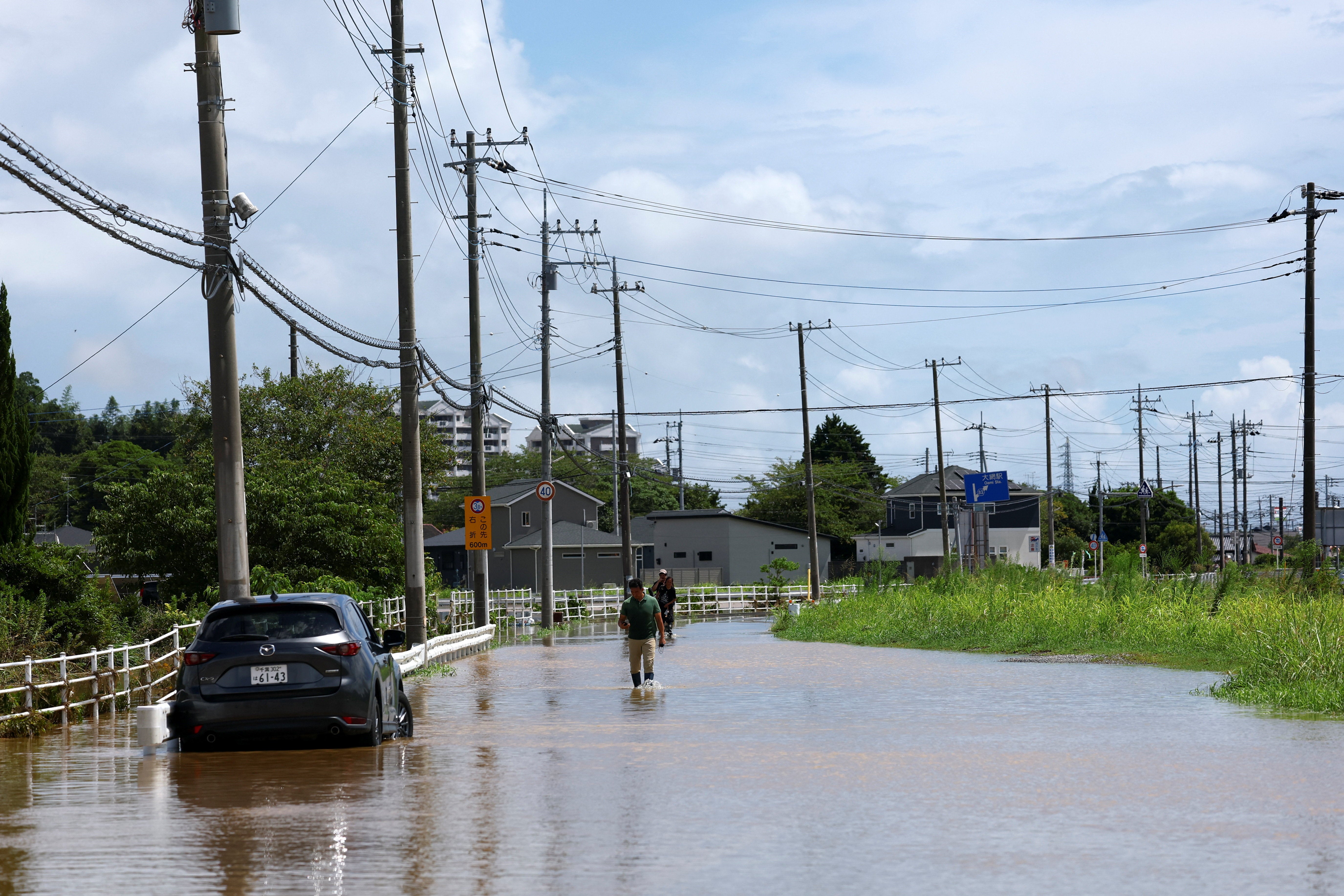 Vecinos de la zona caminan por una zona inundada tras las fuertes lluvias caídas en Oamishirasato, en la prefectura de Chiba, Japón