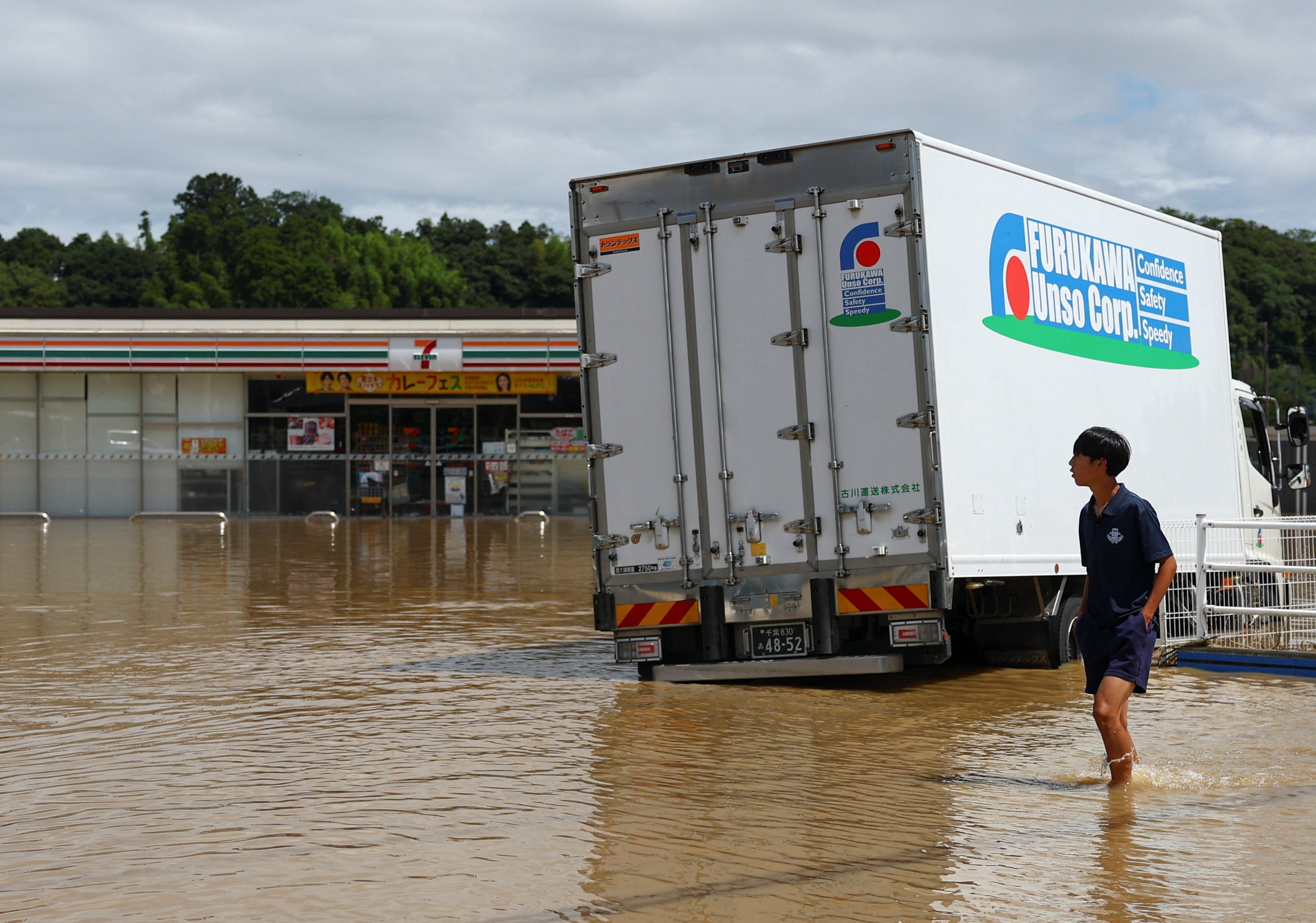 Un vecino camina cerca de una tienda 7-Eleven en una zona inundada tras las fuertes lluvias caídas en Oamishirasato