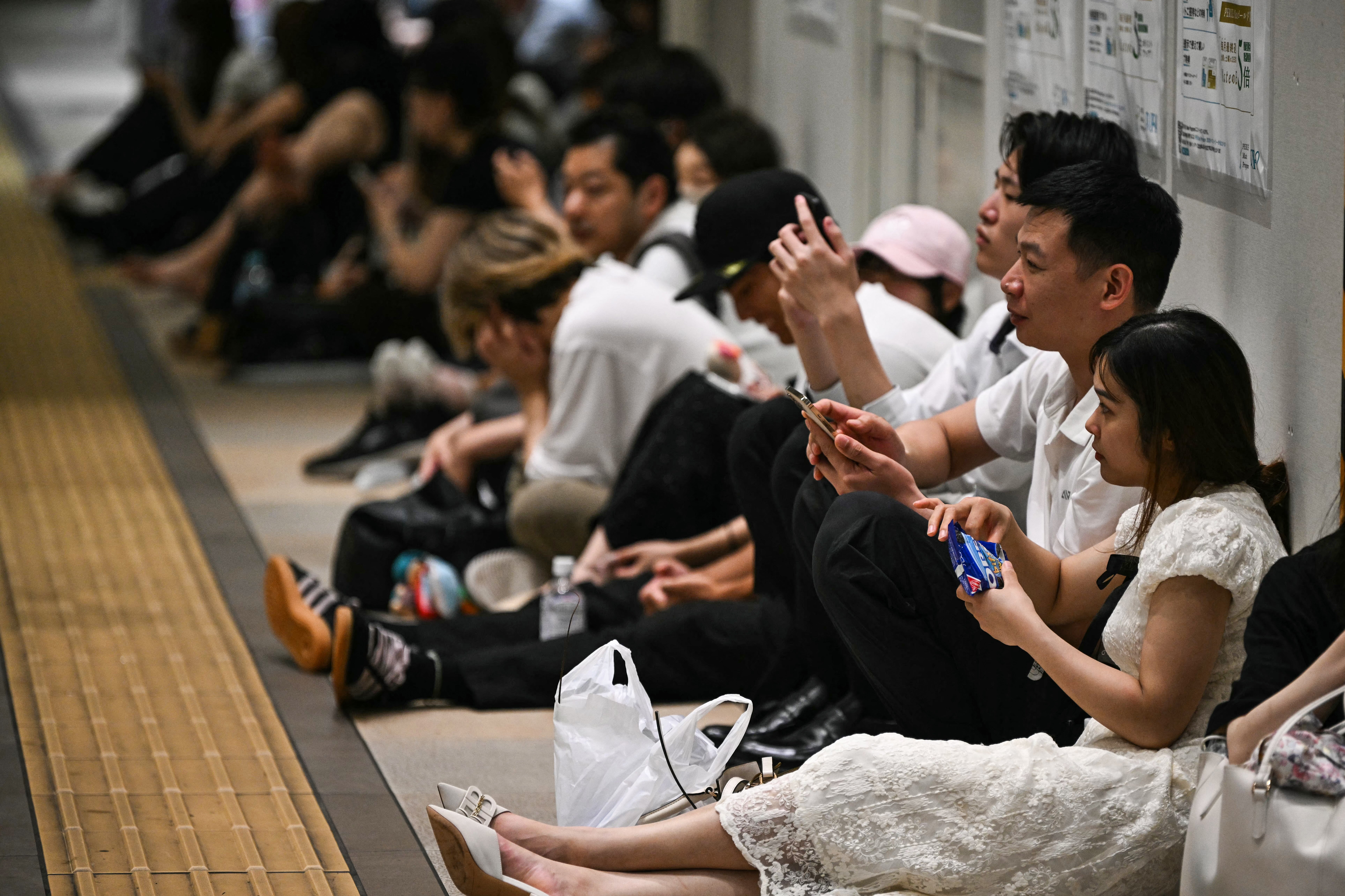 Pasajeros varados se sientan en el suelo en la estación de monorraíl Chiba, en Chiba