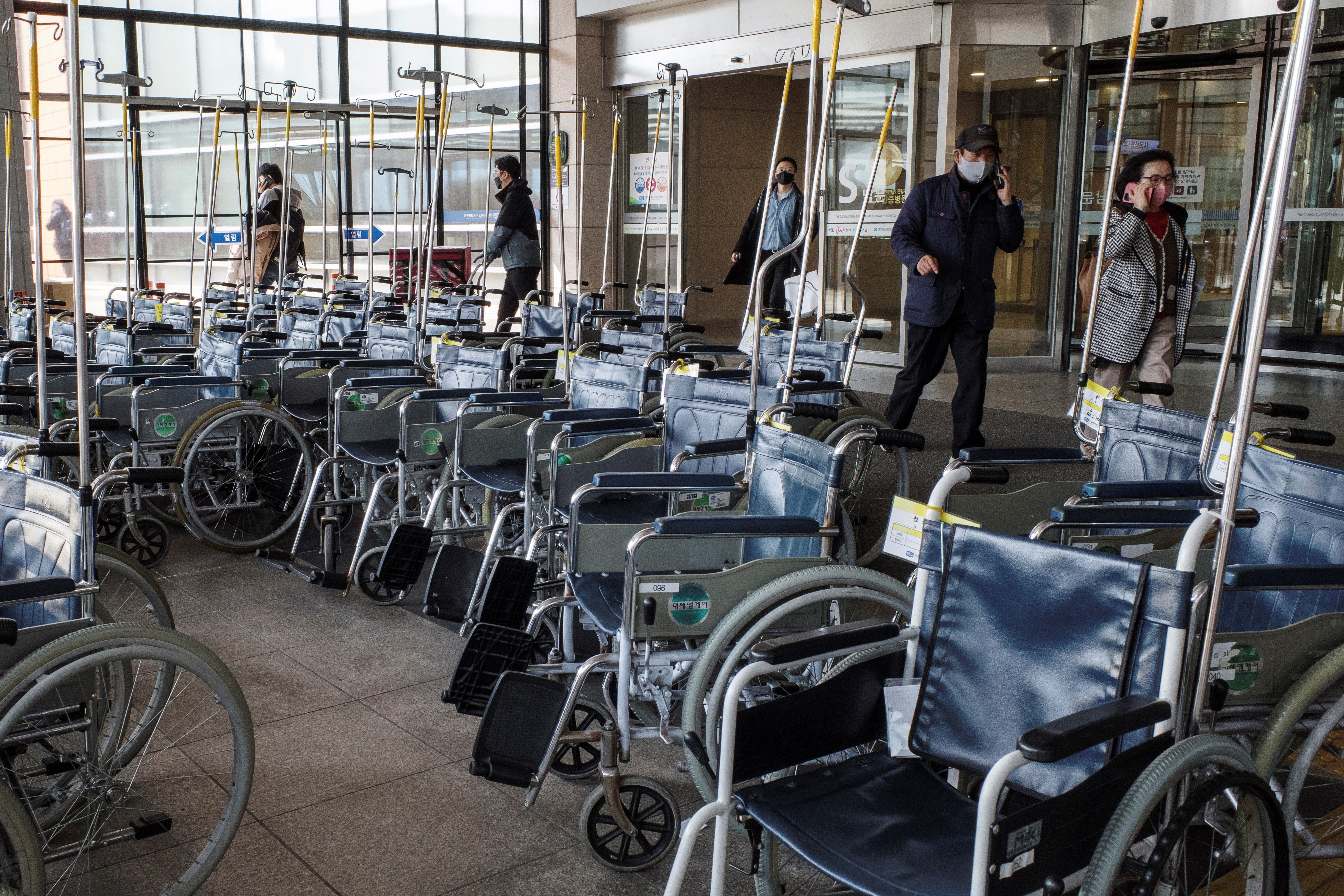 Personas caminan junto a varias sillas de ruedas en un hospital de Seúl