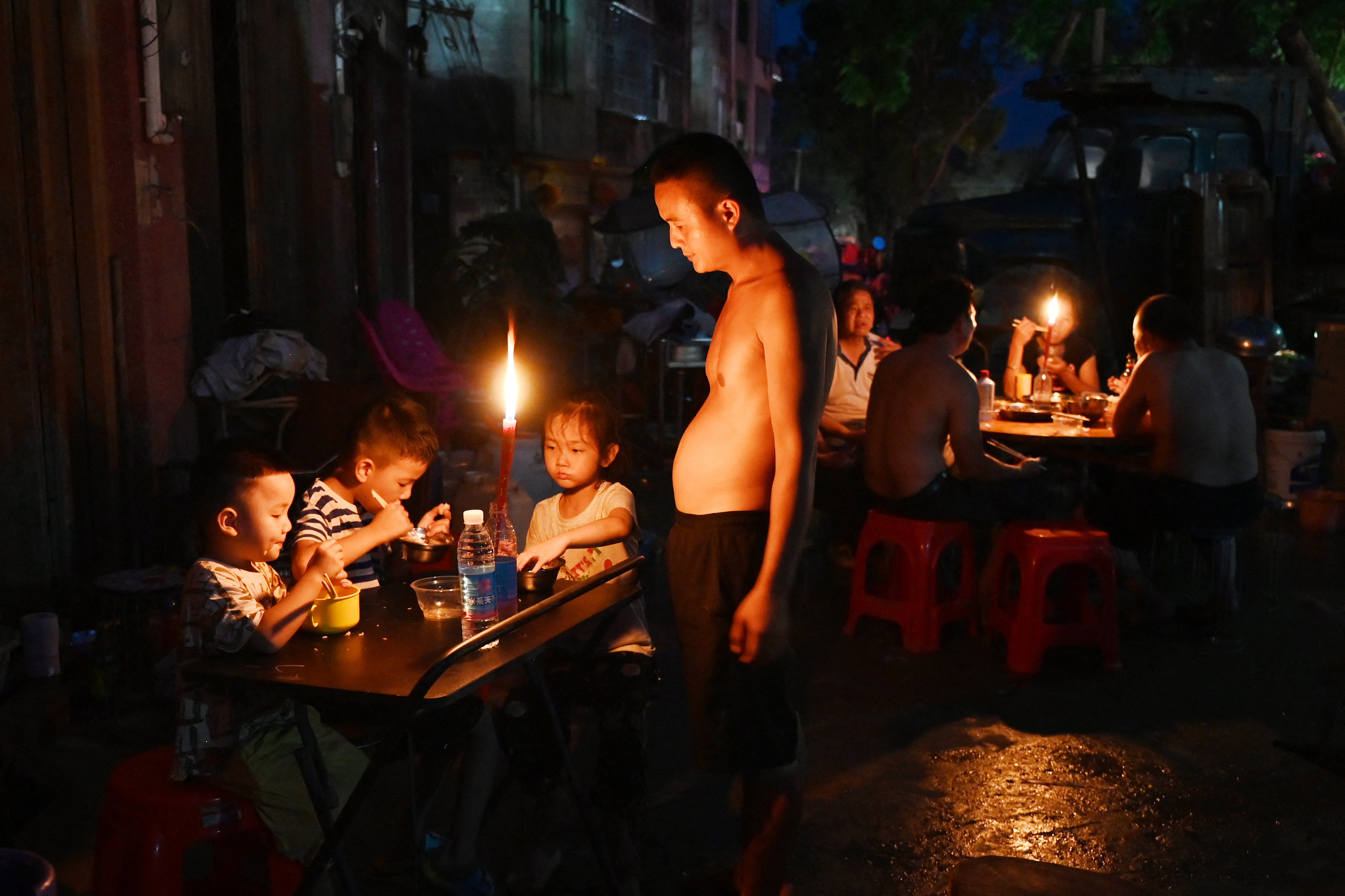 Archivo: un padre observa cómo sus hijos cenan a la luz de las velas frente a una casa en Gantang, China, tras el corte de electricidad provocado por las inundaciones causadas por el desbordamiento de un embalse en la región de Guangxi, al suroeste del país, el 9 de julio de 2026