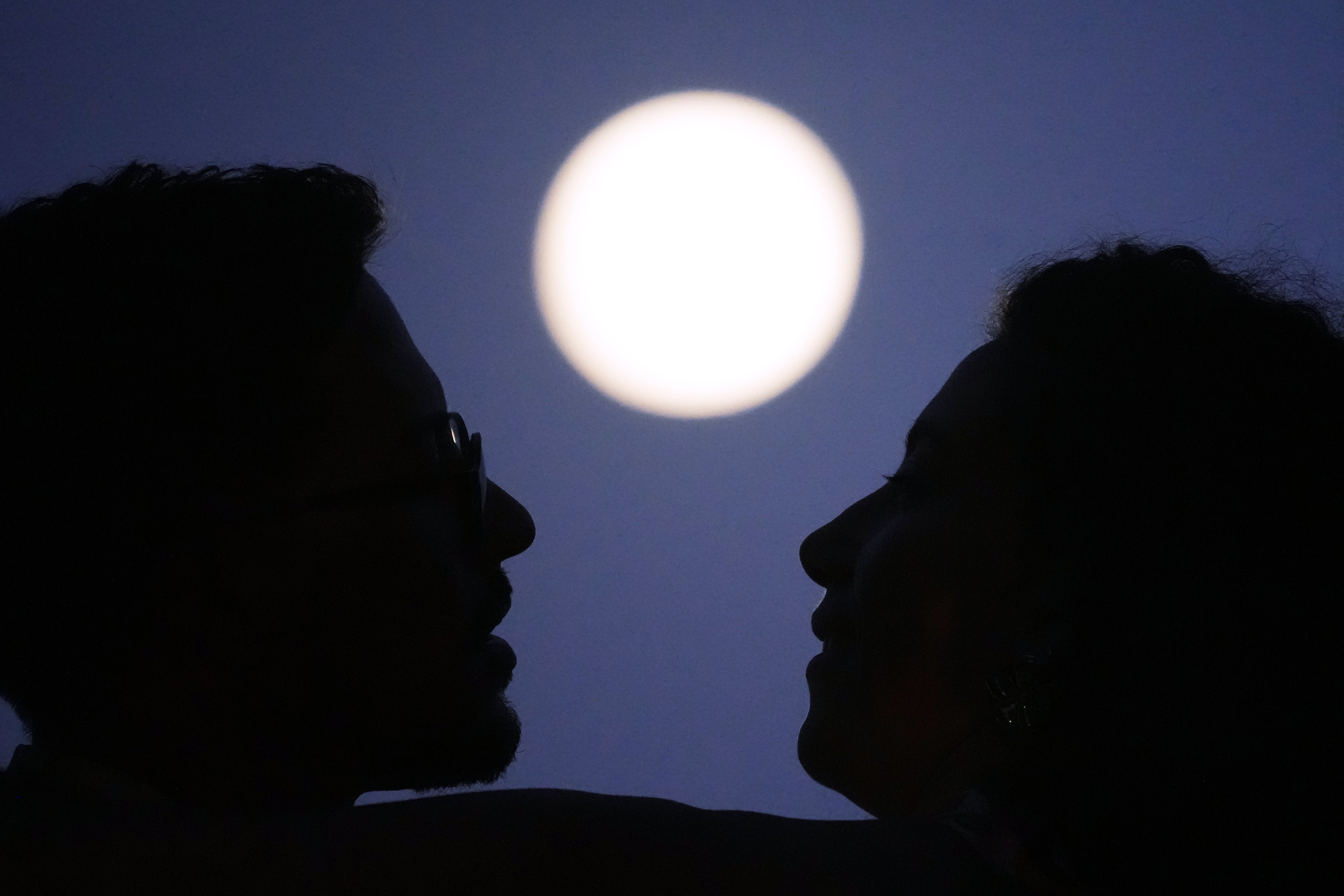 Una pareja se abraza mientras sale la luna llena, unas horas antes de un eclipse lunar, en el mirador de Santa Luzia, en Lisboa