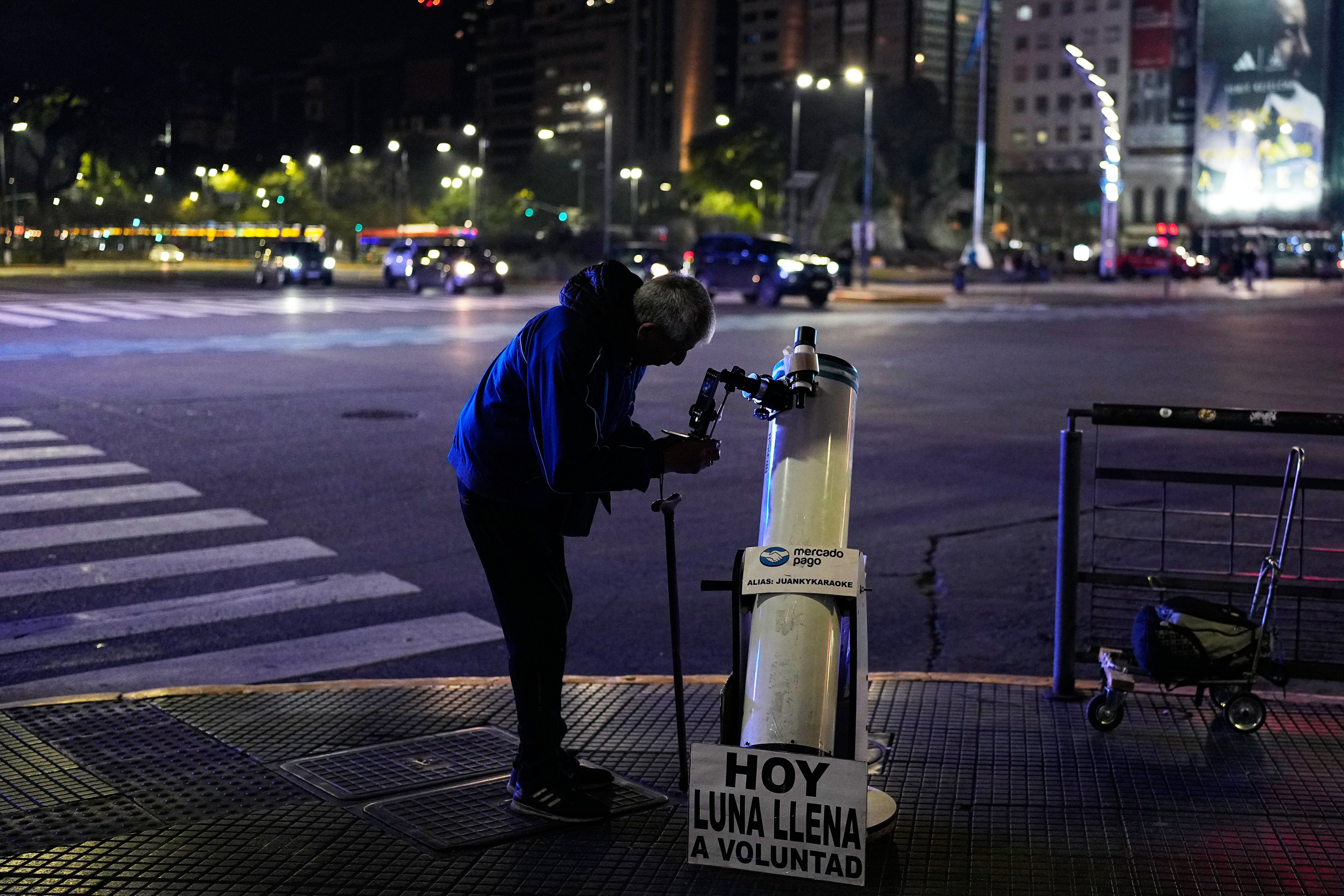 Juan Carlos Sánchez ajusta su telescopio mientras espera a los clientes para ofrecerles la oportunidad de observar la luna en Buenos Aires, Argentina