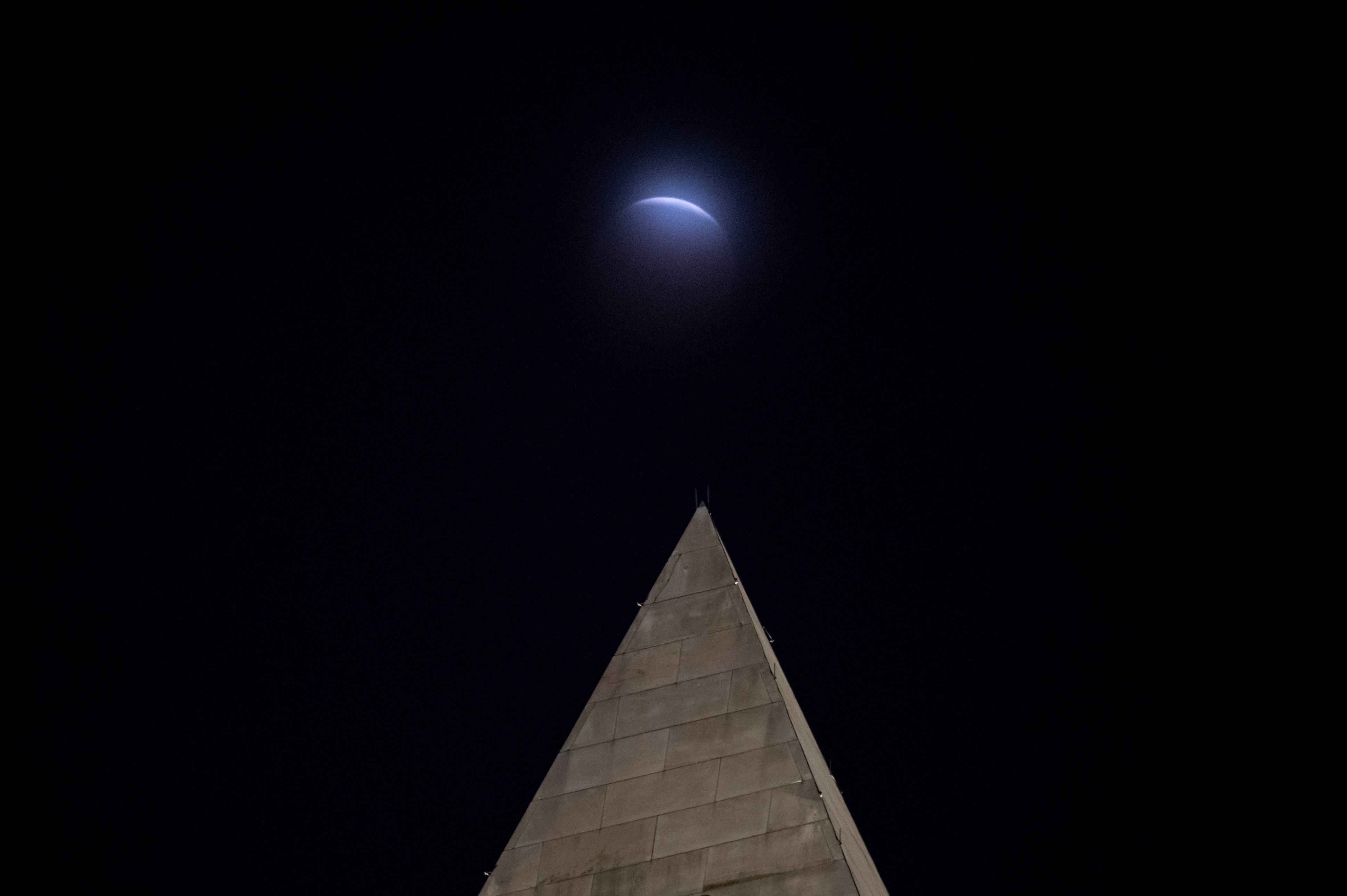 Se observa un eclipse lunar a través de las nubes, detrás del Monumento a Washington