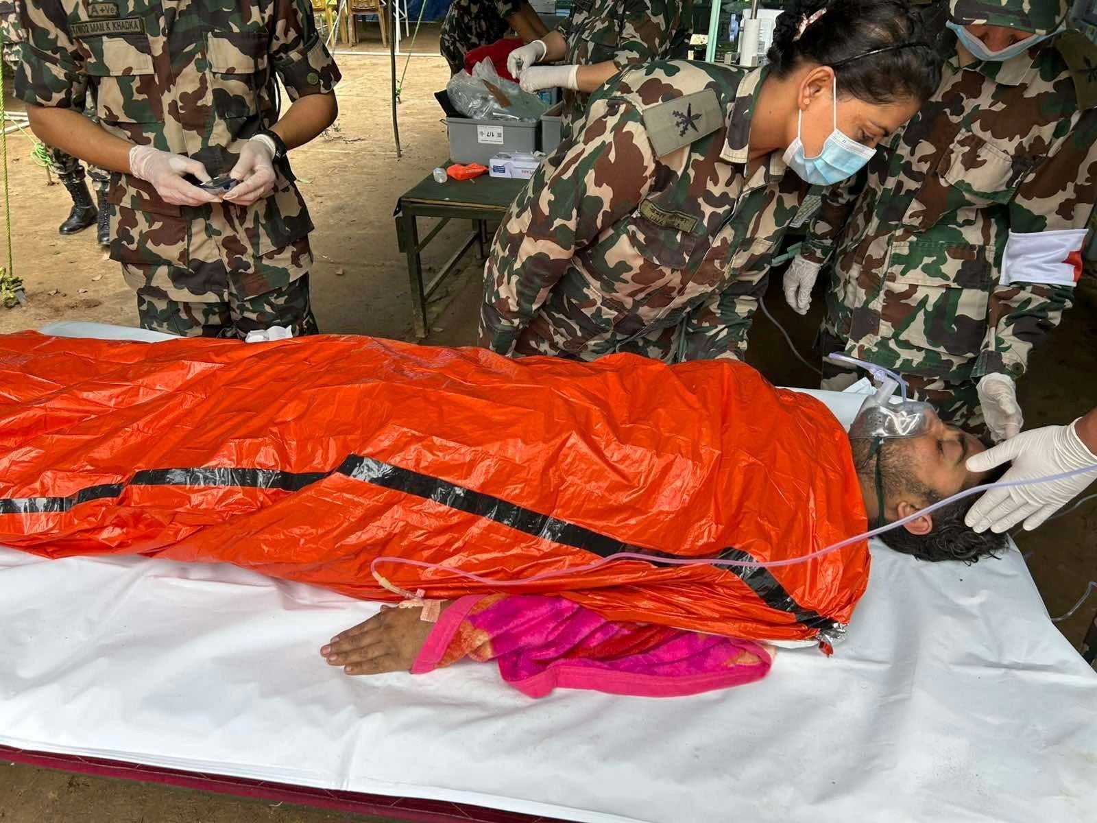 Un sobreviviente, uno de los dos trabajadores rescatados tras quedar atrapados en un túnel del proyecto hidroeléctrico Trishuli 3A debido a las devastadoras inundaciones y deslizamientos de tierra, recibe atención médica