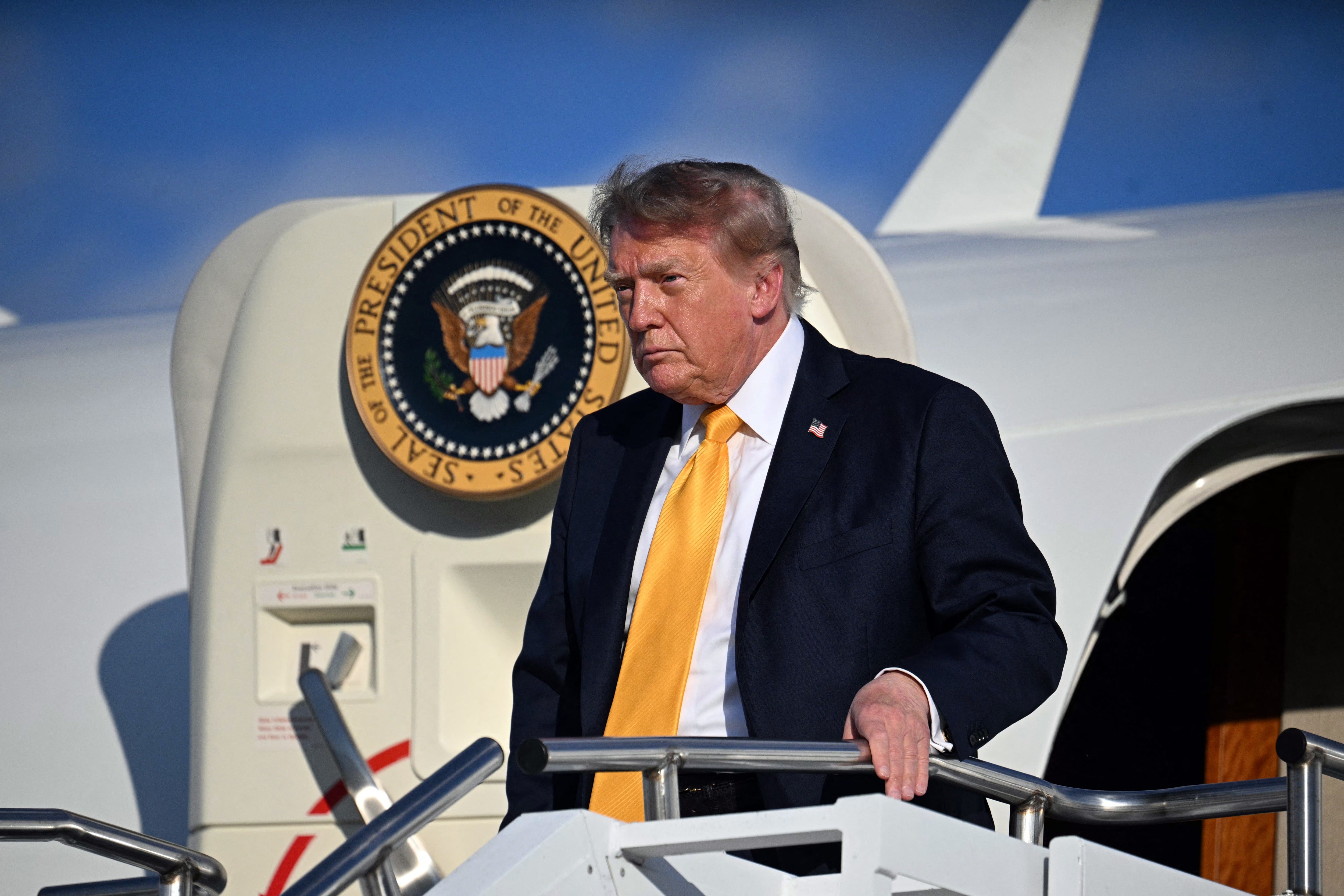 Trump saluda a los periodistas el viernes en la pista de un aeropuerto de Morristown, Nueva Jersey, vestido con un traje azul marino y una corbata amarilla, además de su aparente nuevo look