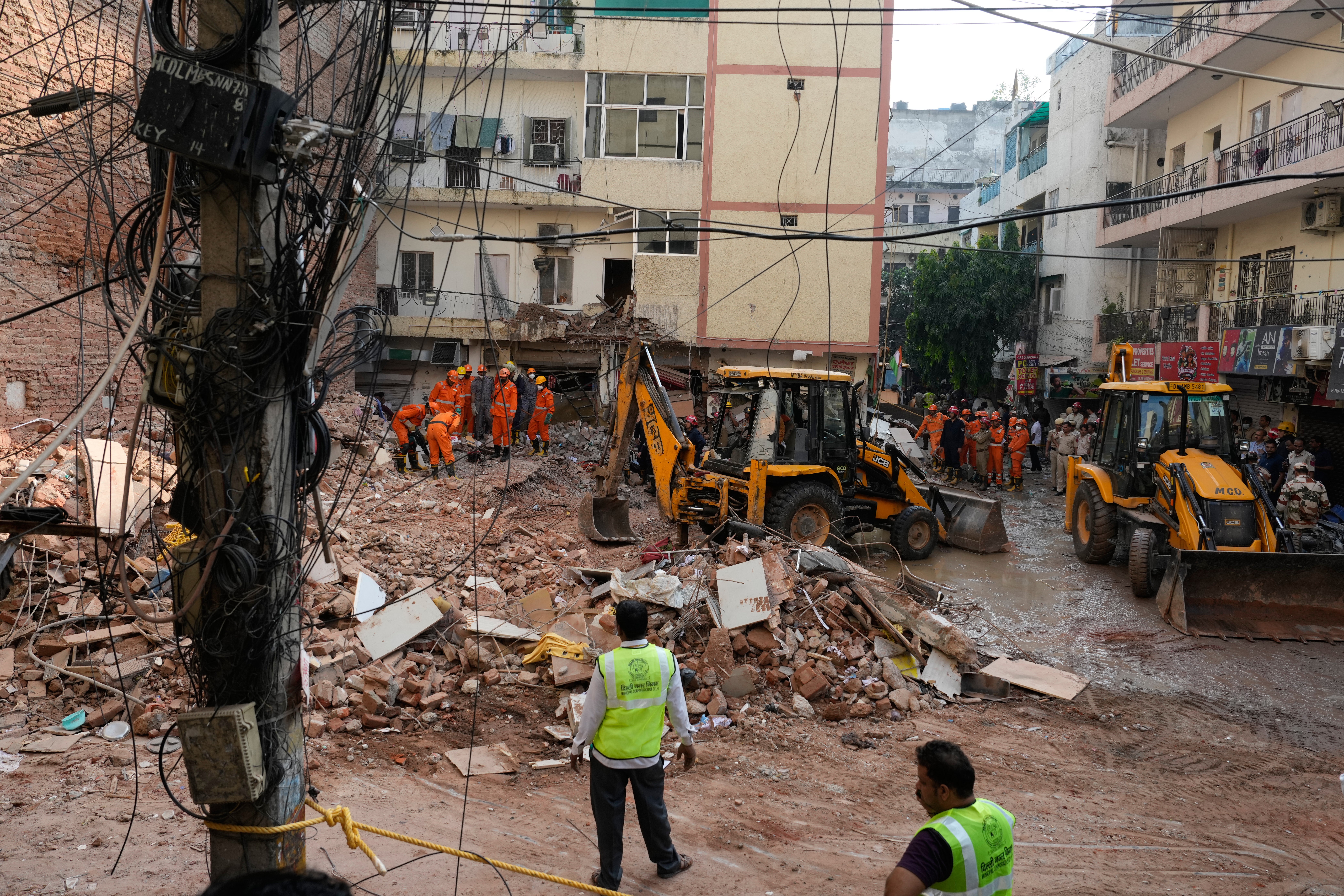 Los equipos de rescate retiran los escombros mientras buscan a personas que podrían estar atrapadas en el lugar donde se ha derrumbado un edificio en Delhi, India