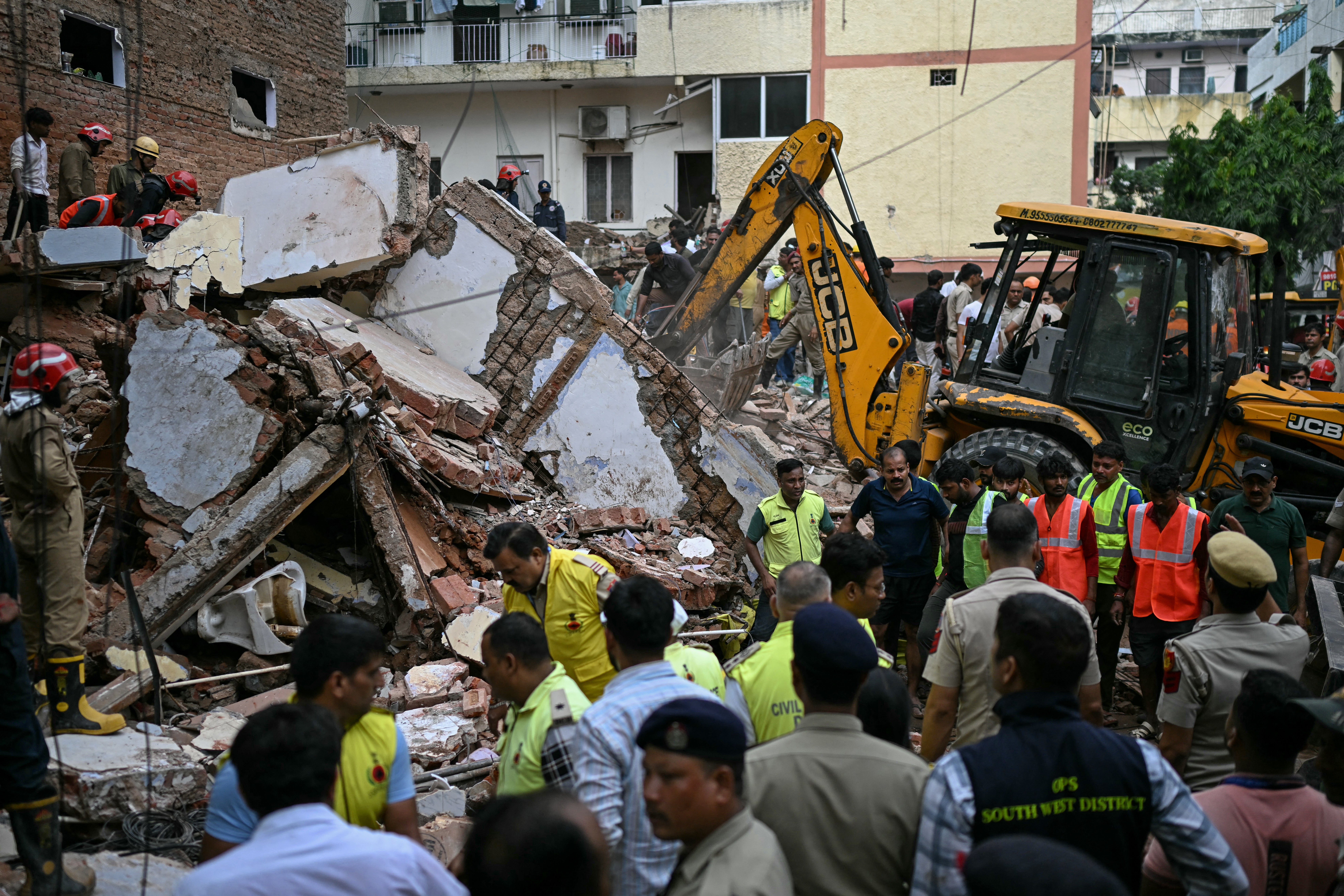Las excavadoras retiran los escombros mientras los equipos de rescate llevan a cabo una búsqueda en el lugar del derrumbe