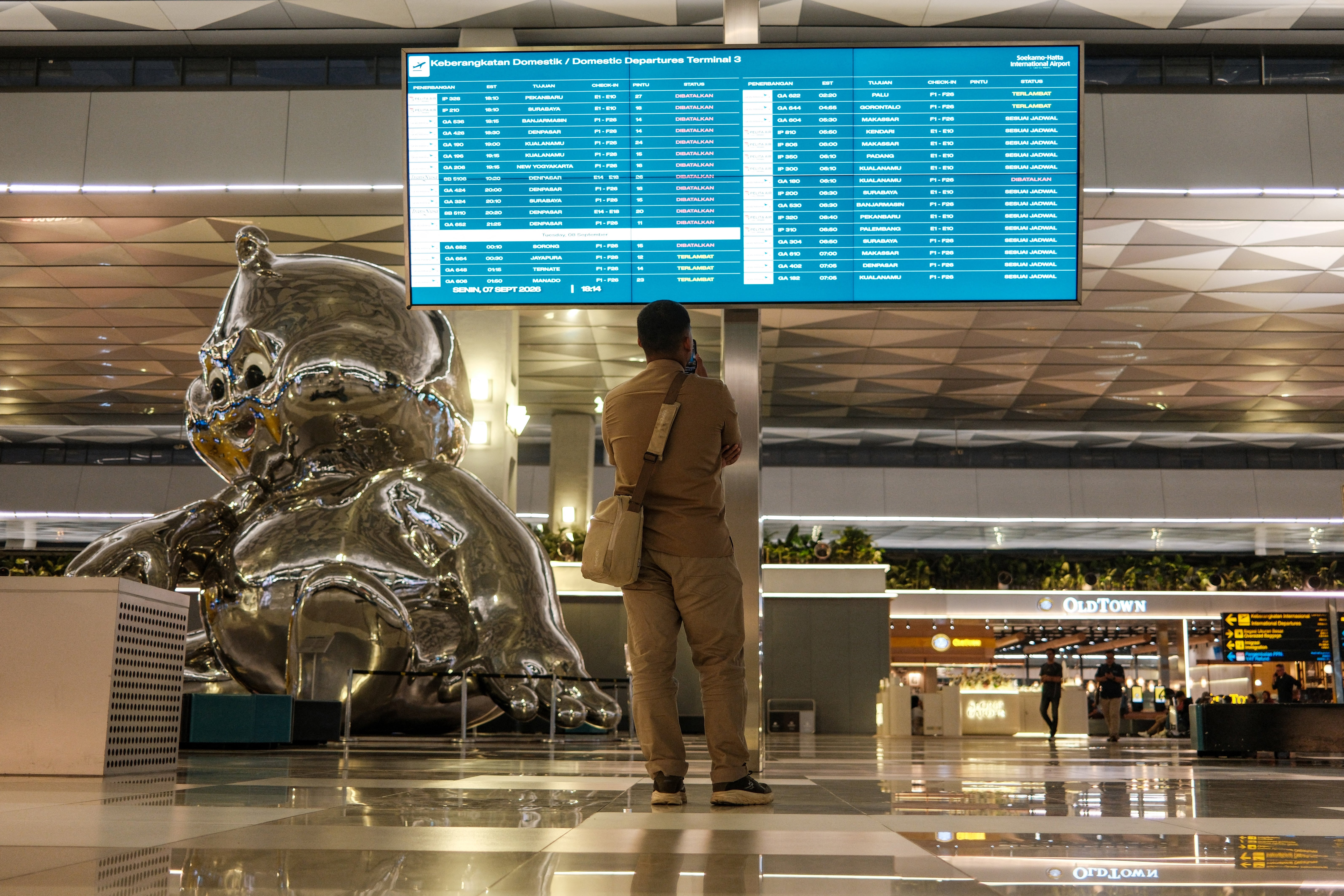 Un pasajero varado consulta una pantalla con información de vuelos en el Aeropuerto Internacional Soekarno-Hatta, en Tangerang, tras las interrupciones provocadas por la erupción del monte Anak Krakatau