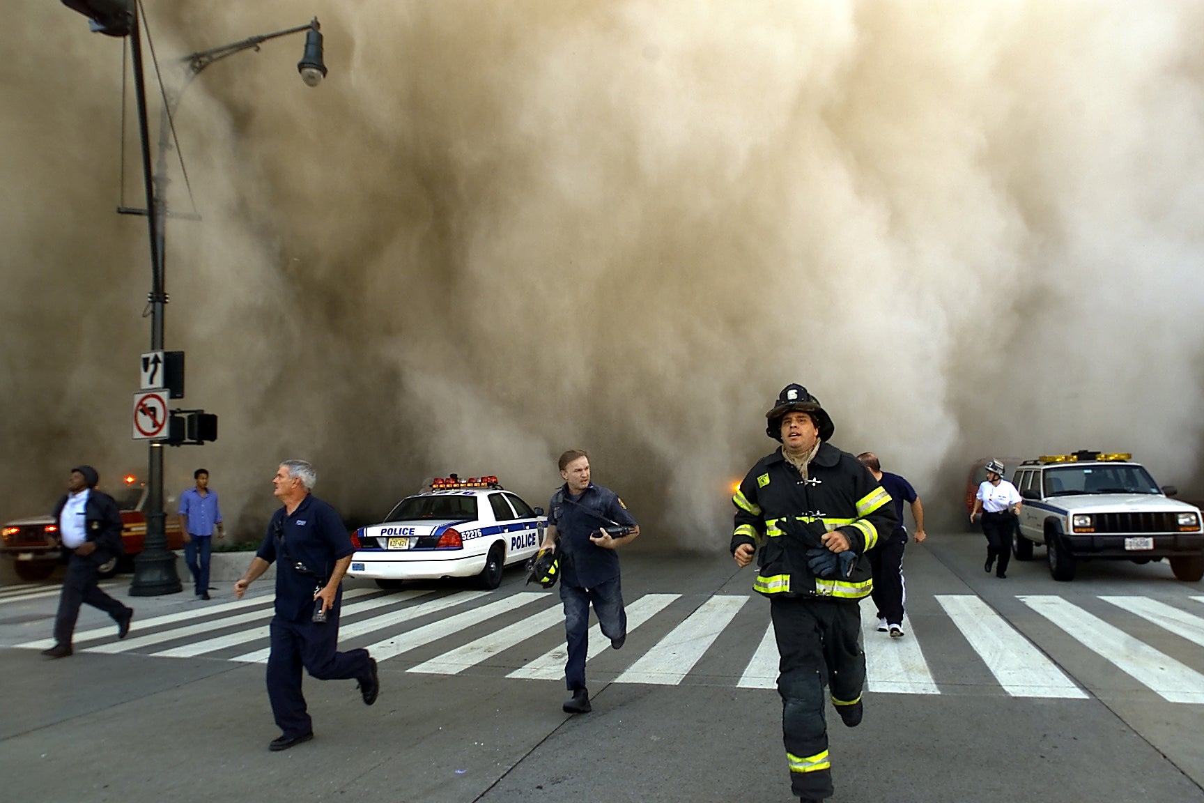 Equipos de emergencia intentan escapar de la nube de polvo provocada por el derrumbe de la Torre Norte del World Trade Center el 11 de septiembre de 2001