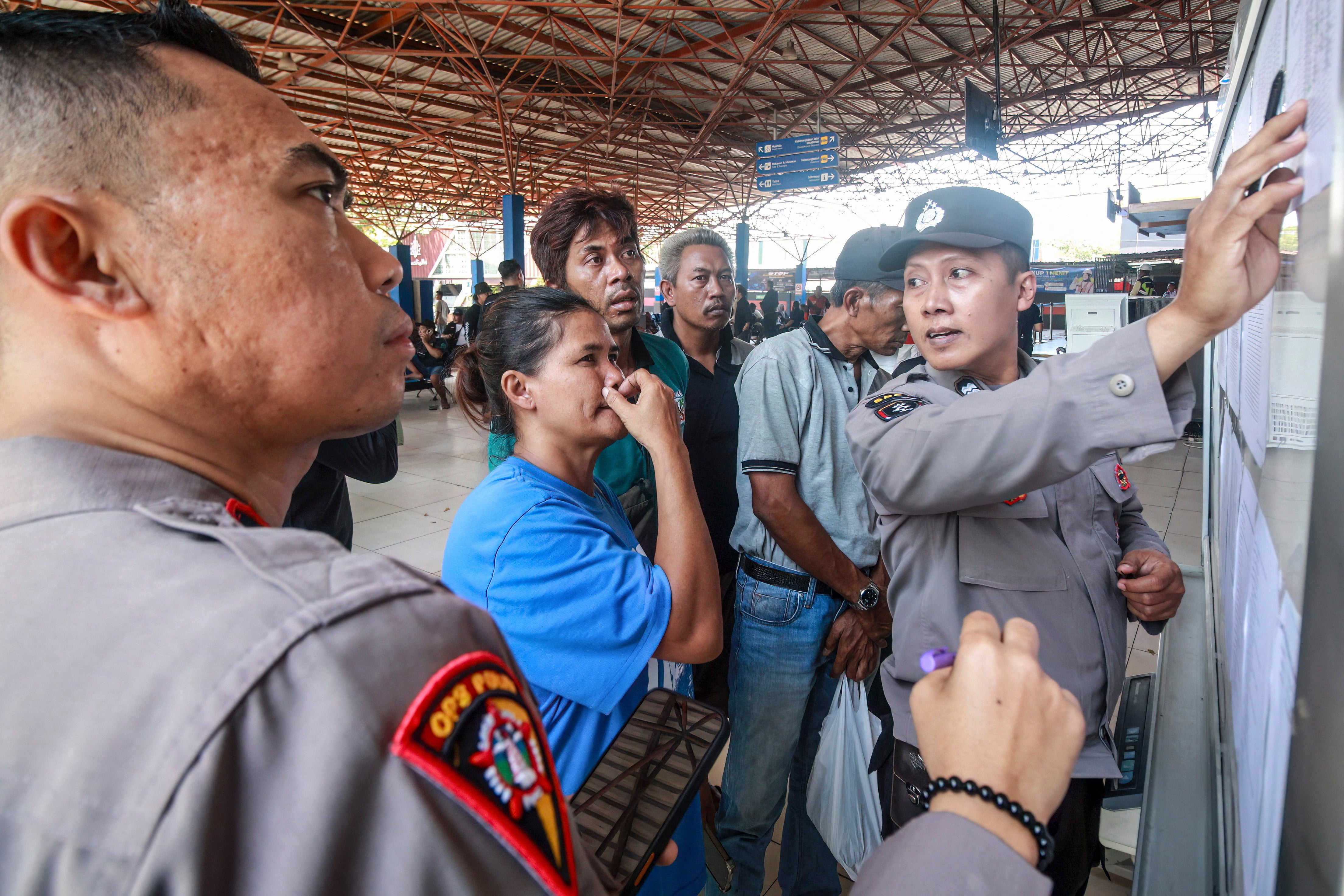 Una mujer reacciona mientras unos agentes de policía muestran una lista de las víctimas del ferry de pasajeros ‘Virgo Transport 8’ en el puerto de Banjarmasin