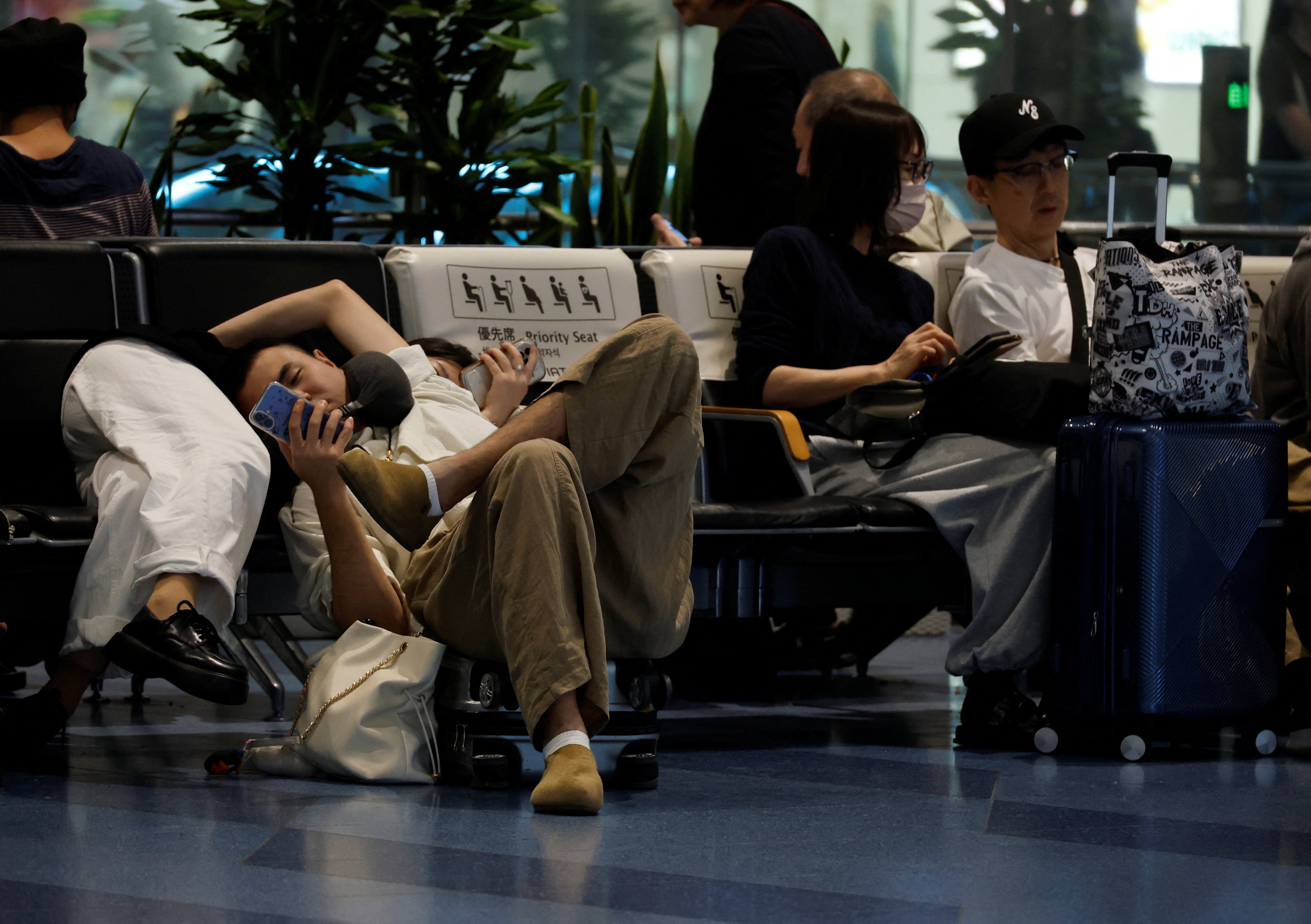Pasajeros descansan en el aeropuerto de Haneda ante los numerosos vuelos retrasados y cancelados por el tifón Dujuan