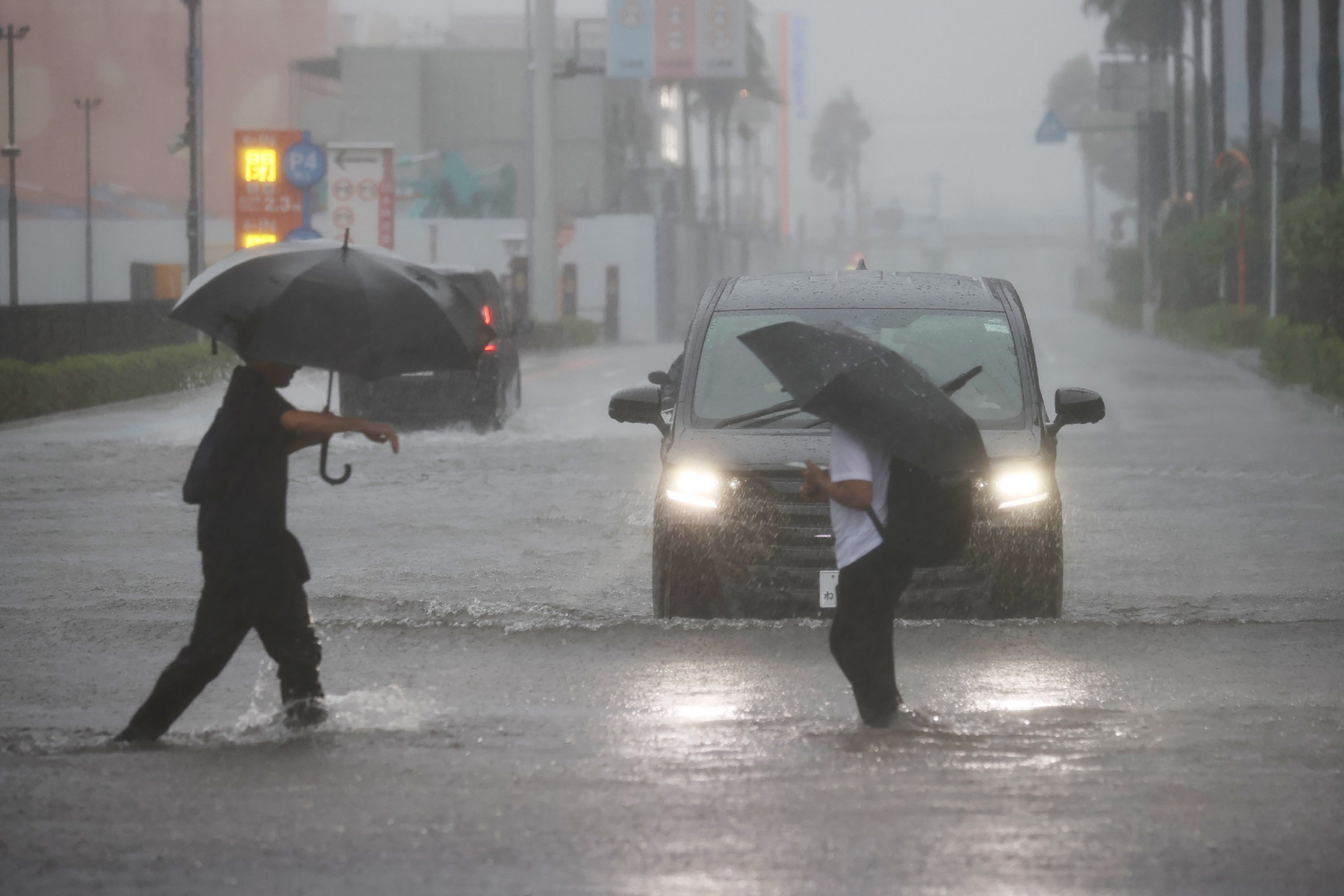 <p>Varias personas cruzan una calle inundada en Funabashi, prefectura de Chiba, Japón</p>