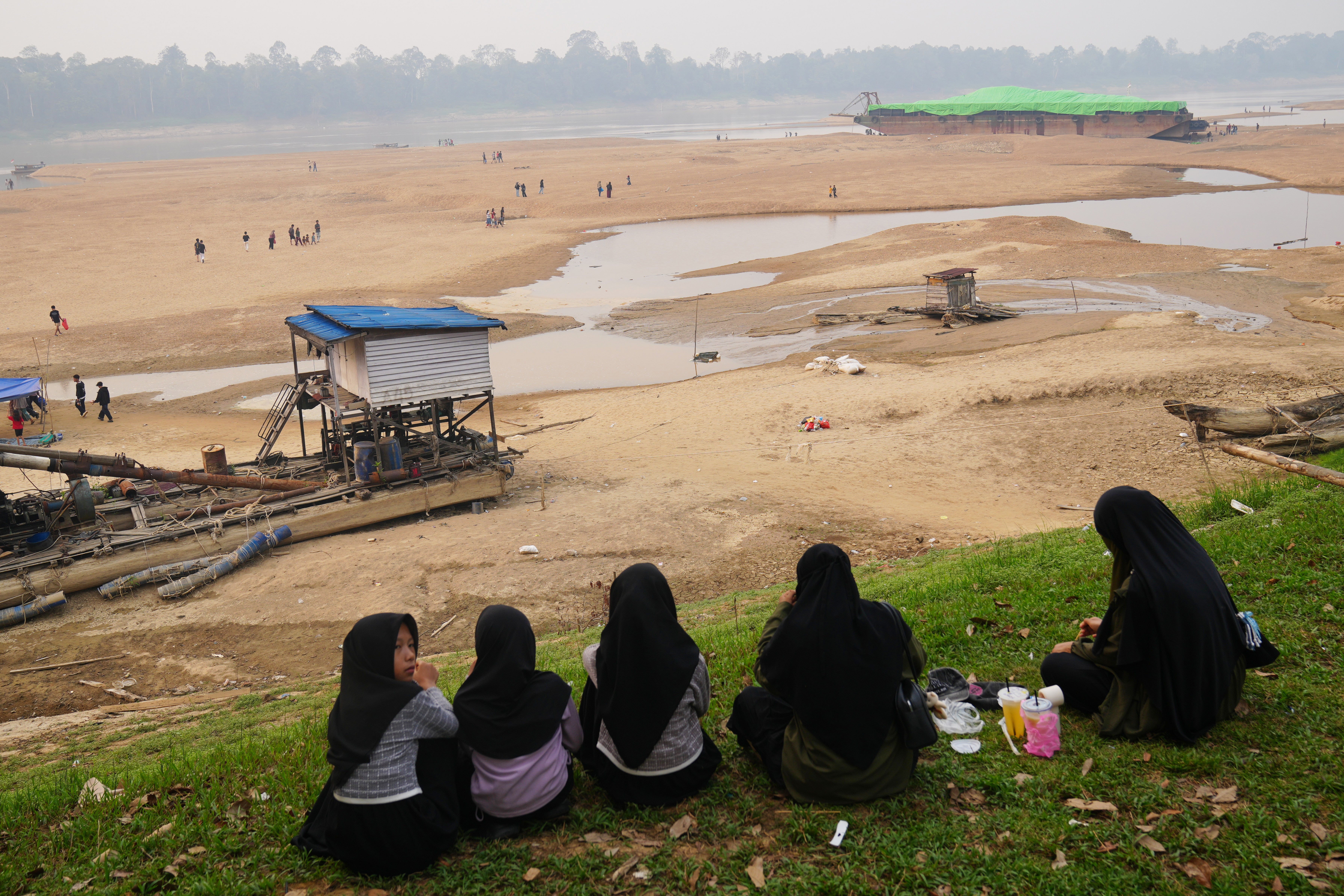 Varias personas observan una barcaza (al fondo, a la derecha) que quedó varada en el lecho seco del río Kapuas debido a una sequía en Sekadau, Kalimantan Occidental, Indonesia
