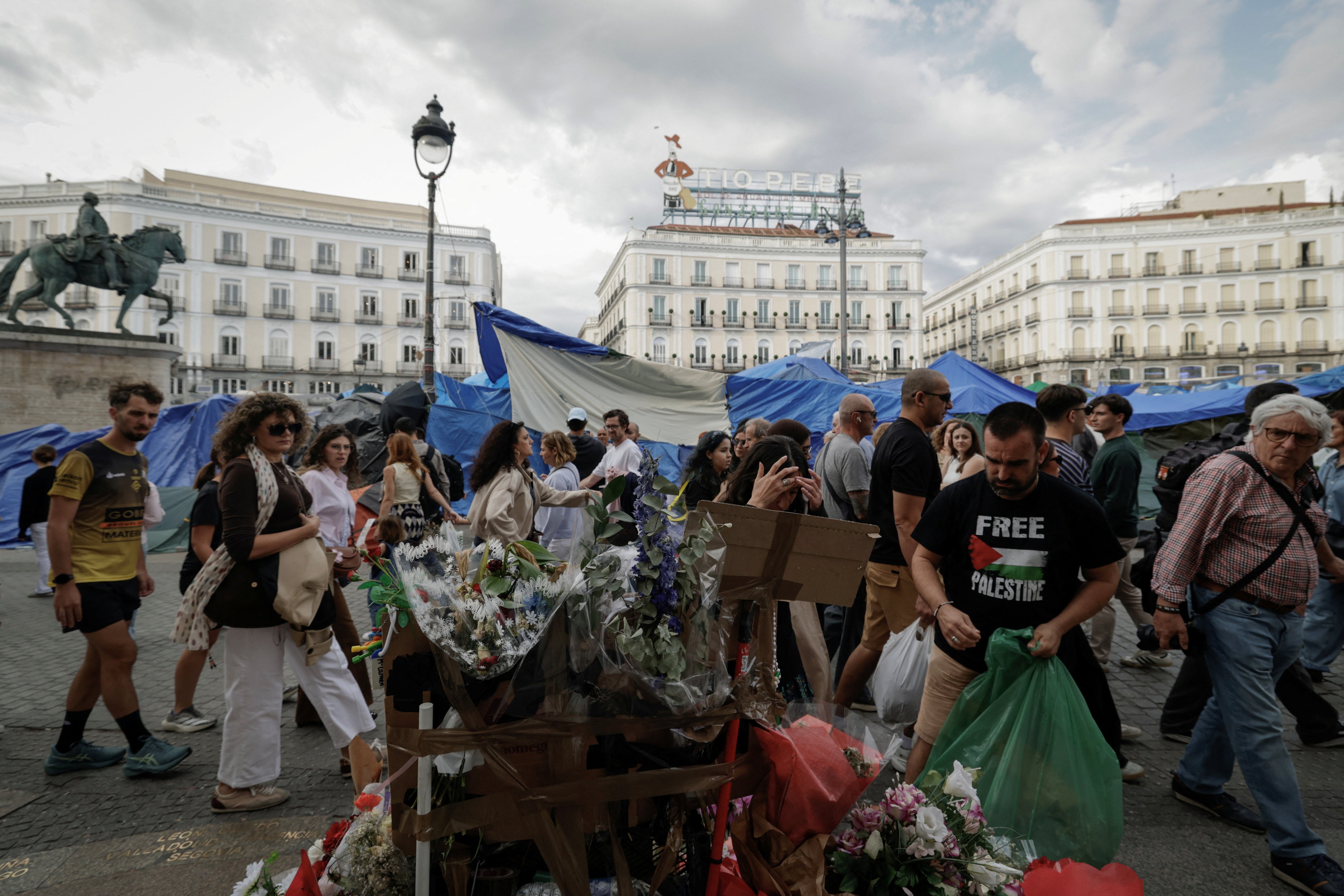 Varias personas pasan junto a un memorial improvisado en homenaje a la fallecida Maricarmen, frente a la sede del Gobierno de la Comunidad de Madrid, el sábado