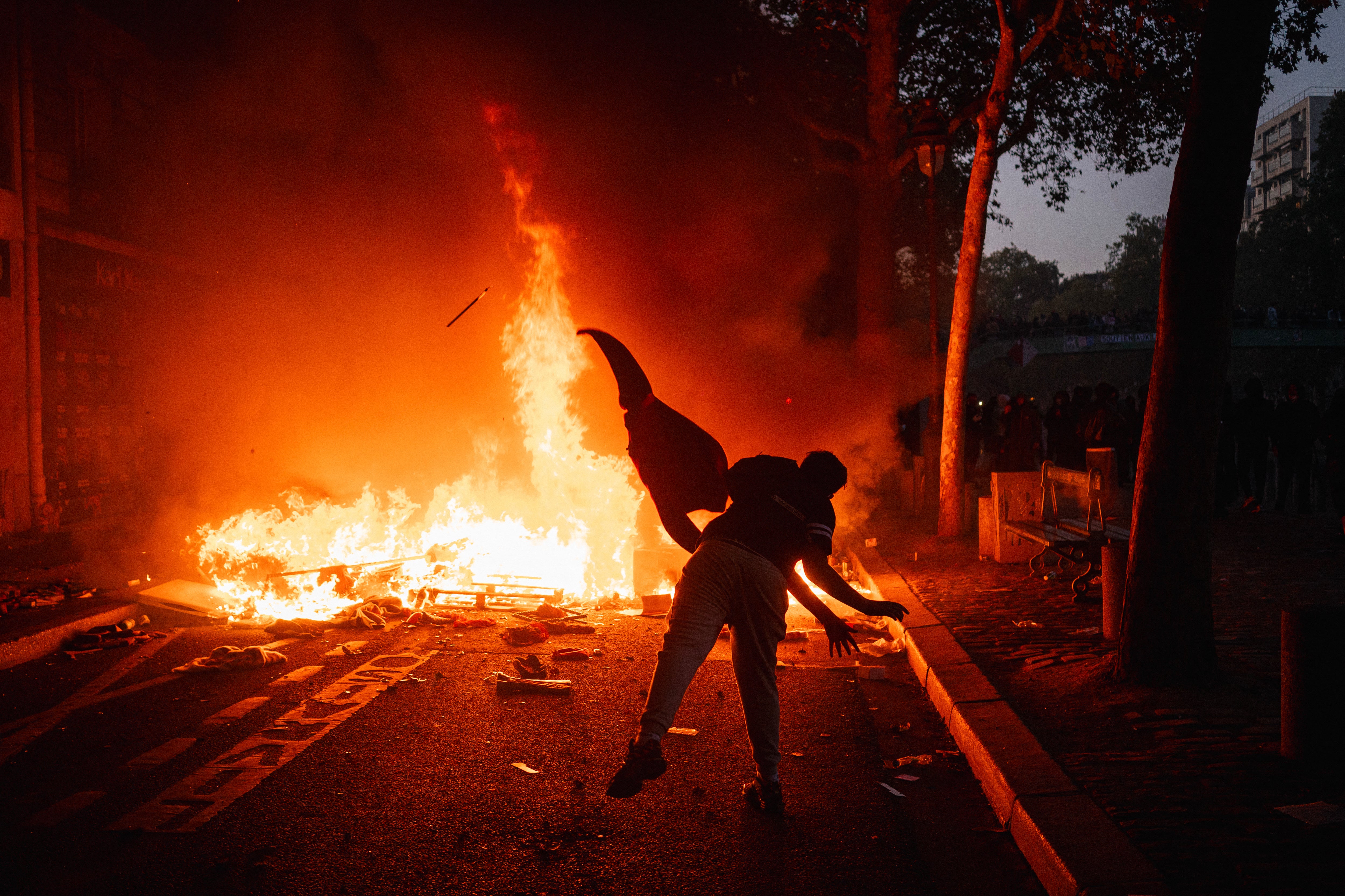 Un manifestante alimenta una hoguera con material combustible junto al canal Saint-Martin durante una protesta contra el alto costo de vida en París, el 17 de octubre