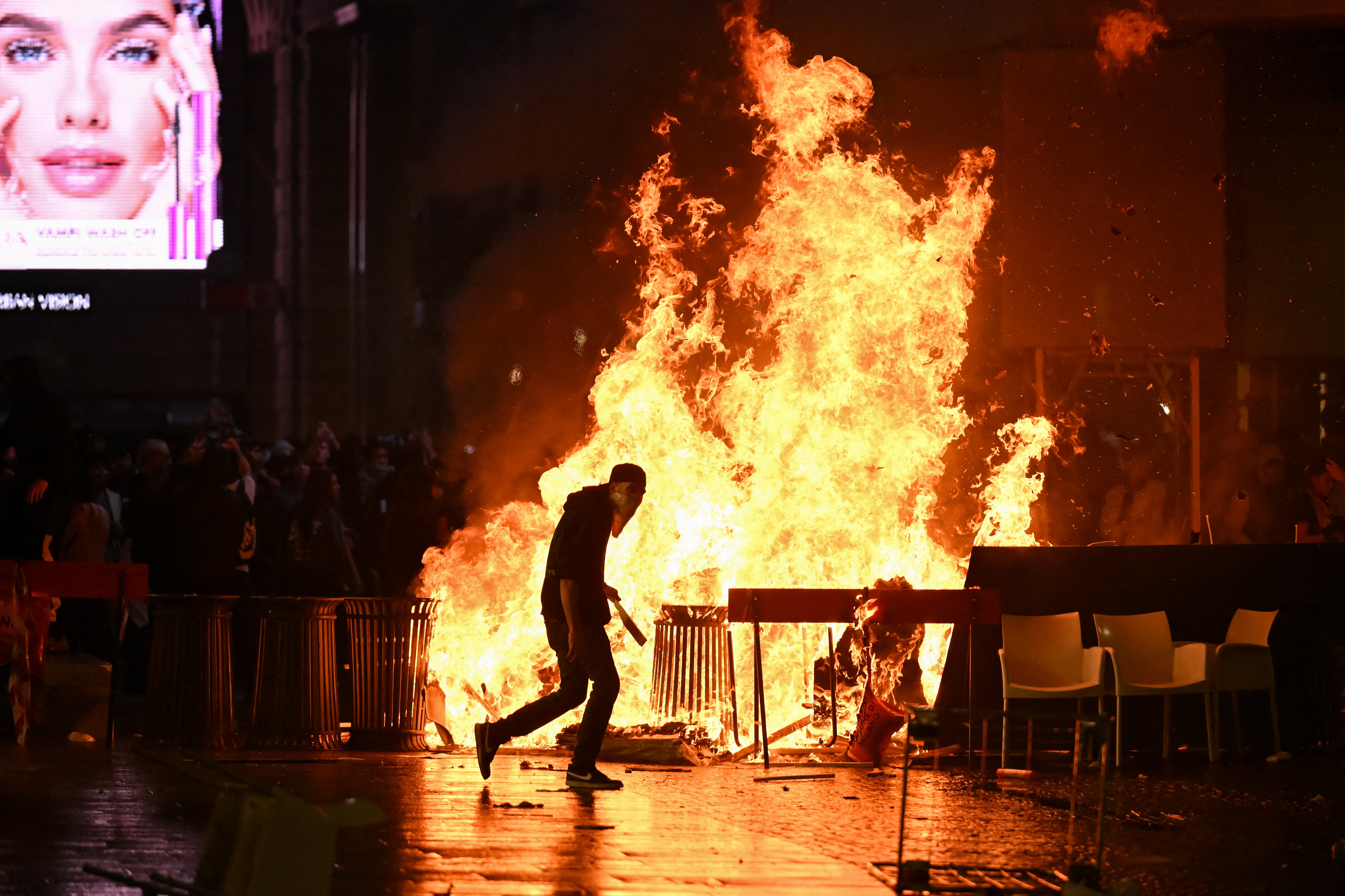 Prenden fuego a una barricada de cartones y basura mientras los manifestantes se enfrentan a la policía durante una protesta contra el Gobierno organizada por el movimiento Italia in Piazza, en la Plaza de la Catedral de Milán