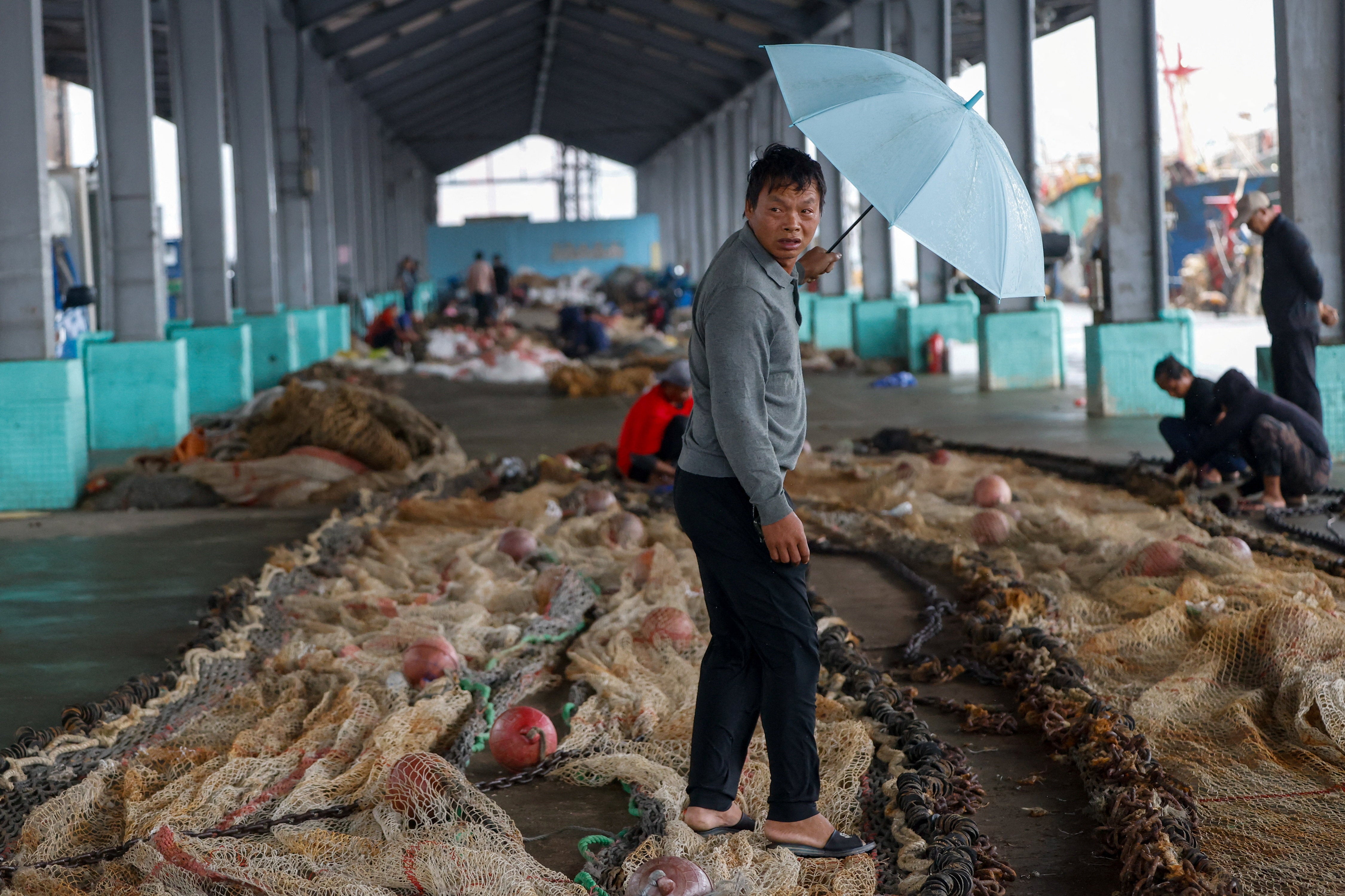Un pescador camina entre redes de pesca en un puerto de Keelung, Taiwán, ante la llegada del tifón Champi, el 23 de octubre de 2026
