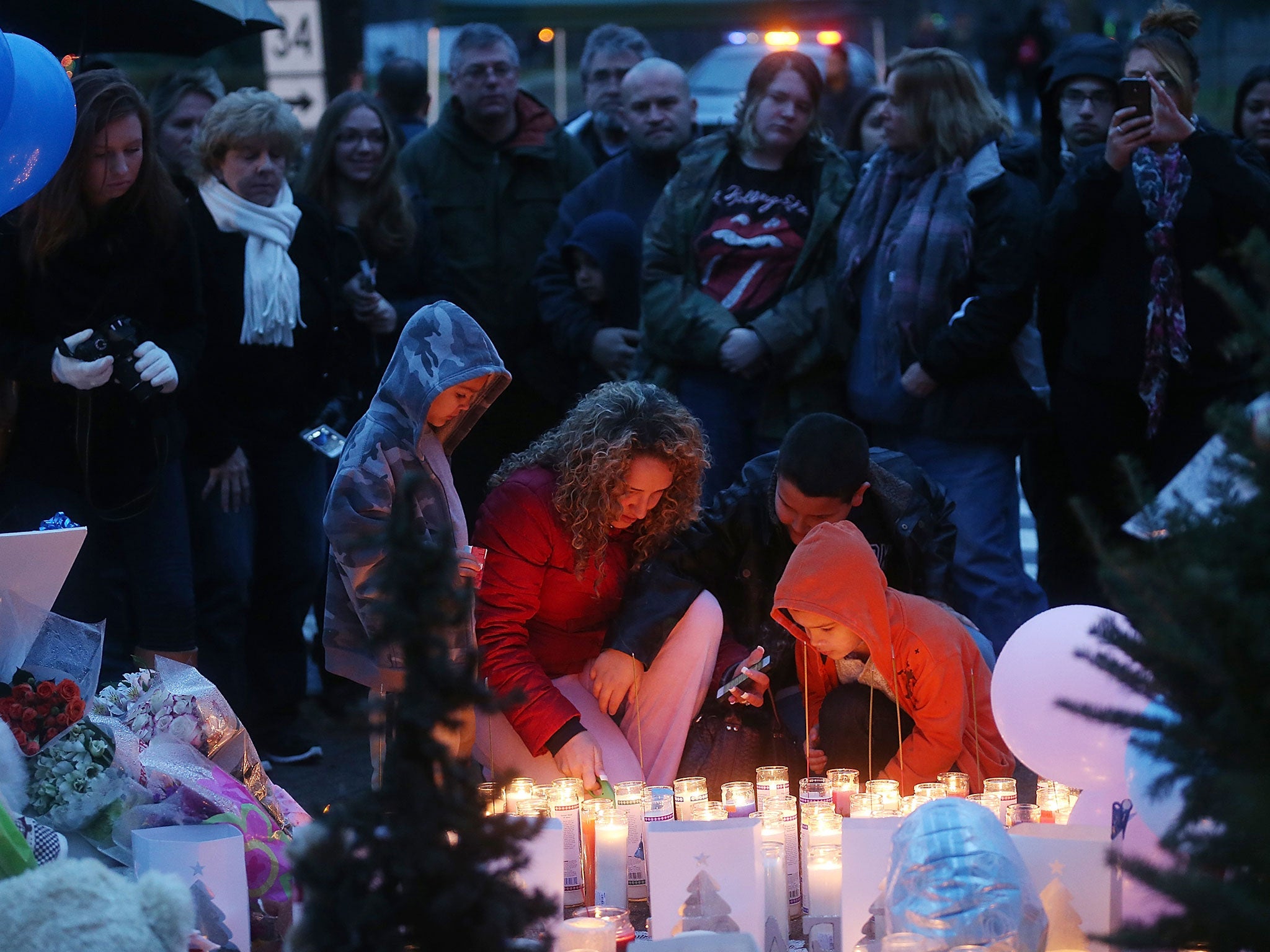 La gente se reúne en un monumento a las víctimas tras el tiroteo masivo en la escuela primaria Sandy Hook de Newtown en diciembre de 2012