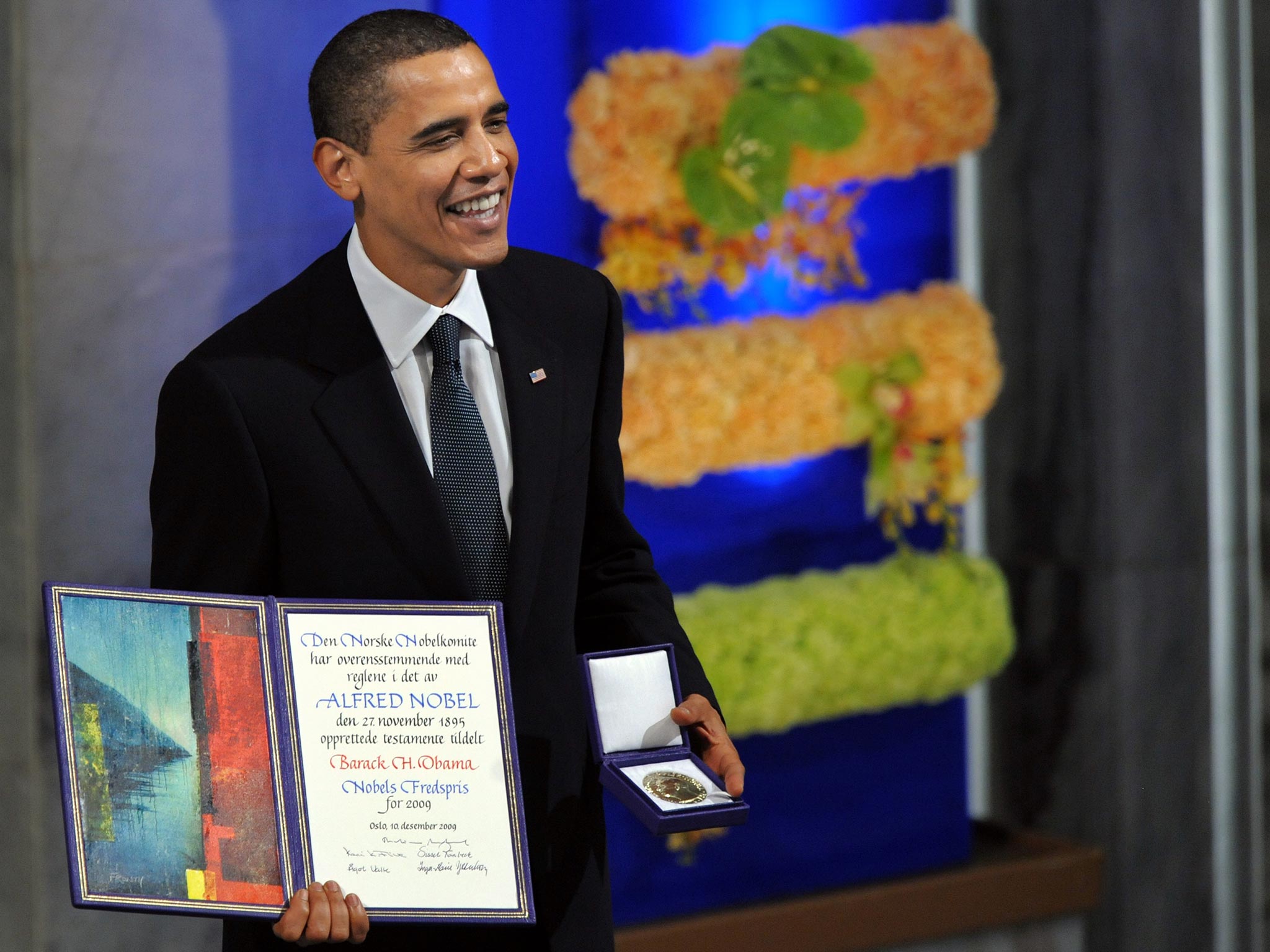 El presidente de Estados Unidos, Barack Obama, galardonado con el Premio Nobel de la Paz, sonríe en el podio con su diploma y medalla de oro durante la ceremonia del Nobel en el Ayuntamiento de Oslo el 10 de diciembre de 2009