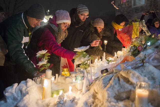La gente coloca velas durante una vigilia en la ciudad de Quebec el lunes por las víctimas del tiroteo mortal del domingo en una mezquita de la ciudad de Quebec.